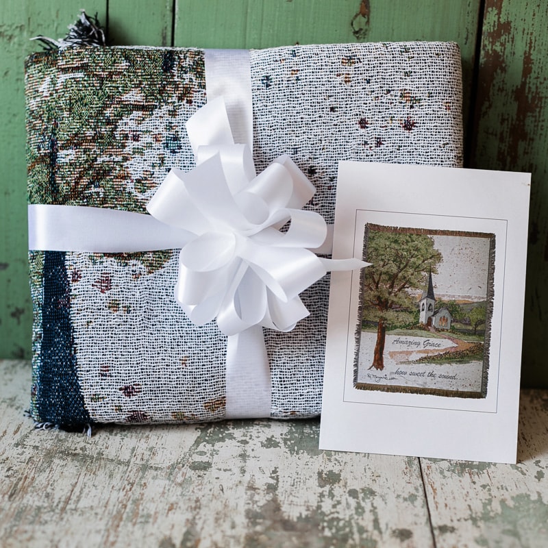 Wrapped gift with a white ribbon and a greeting card beside it