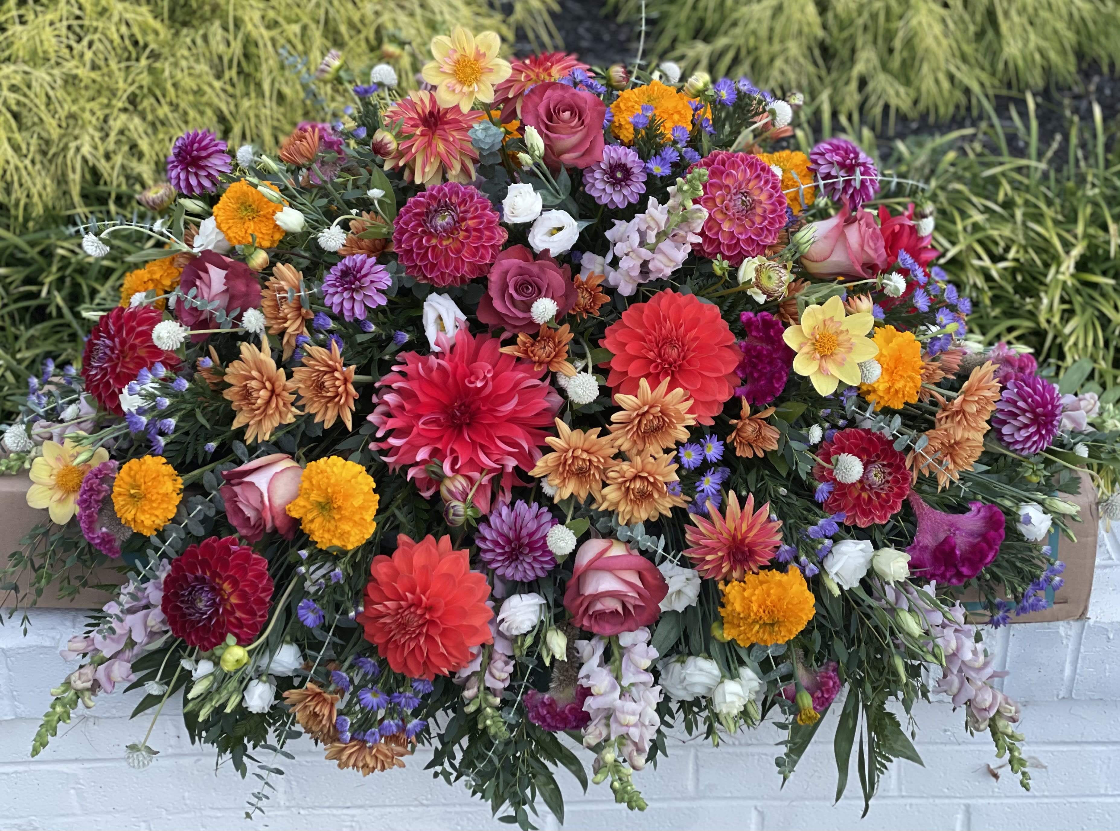 Large colorful floral arrangement with dahlias, roses, and marigolds