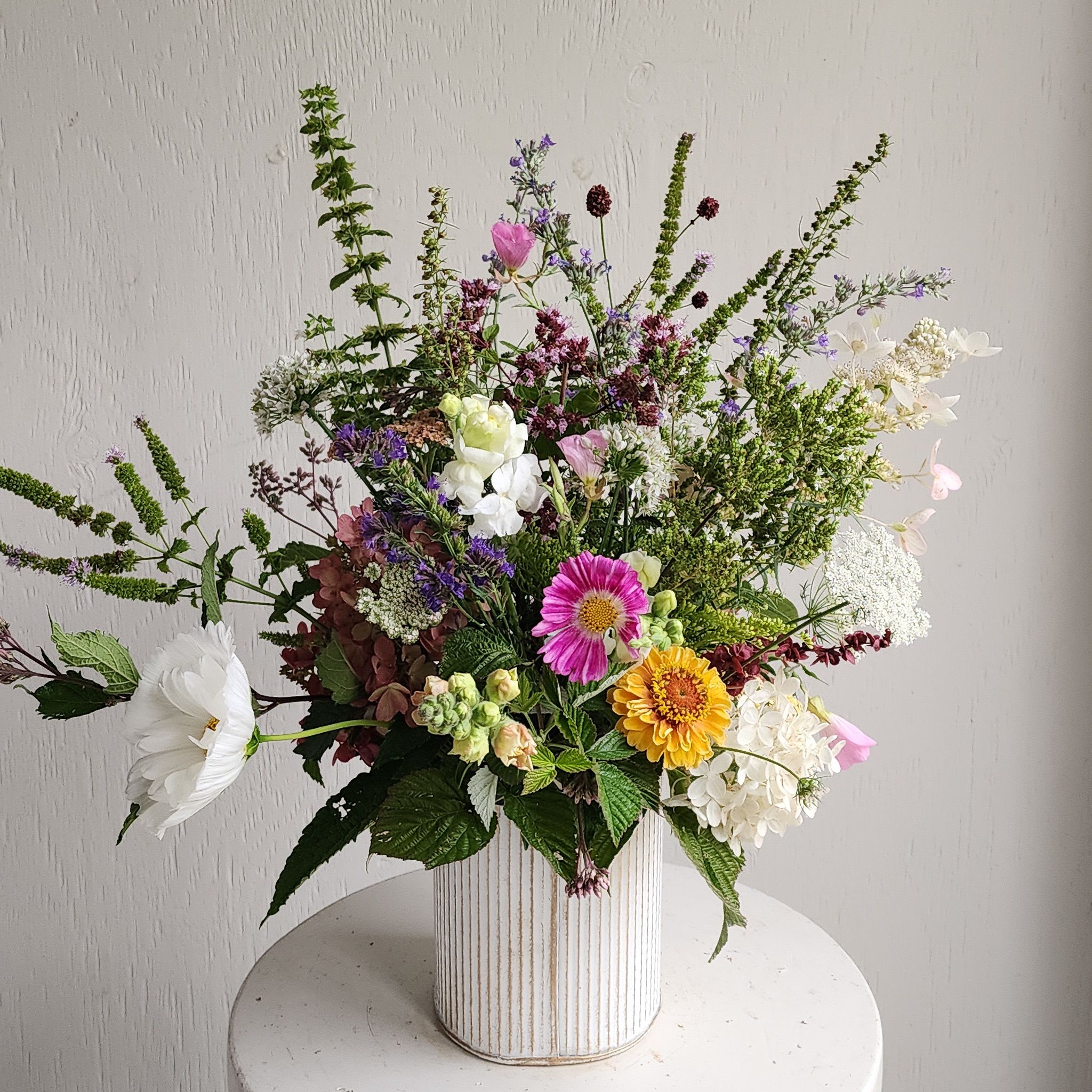 Mixed bouquet in a ribbed white vase with pink, white, yellow, and purple flowers