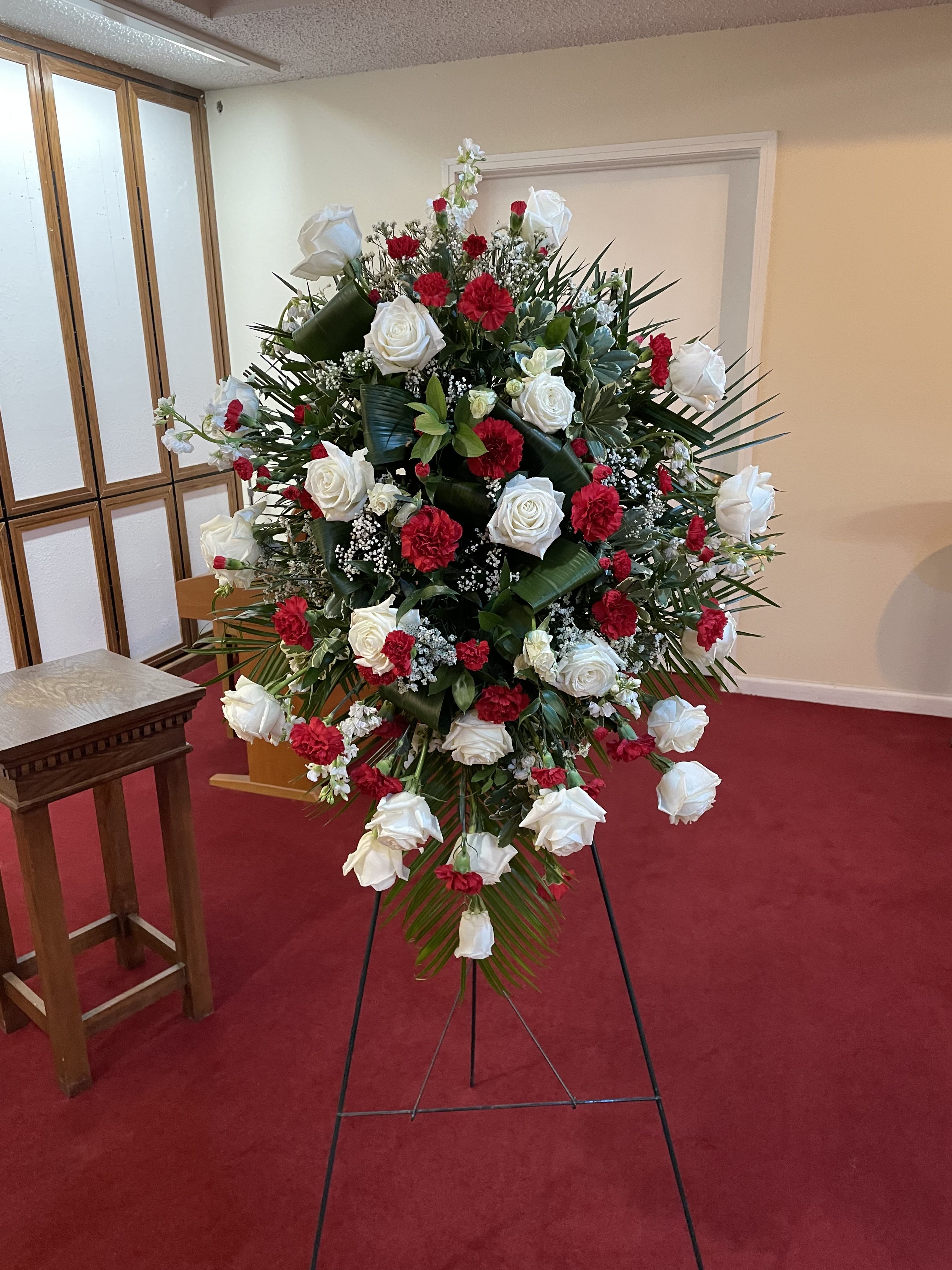Traditional Red and White Sympathy Standing Spray - A traditional red and white standing sympathy spray.  Includes: Easel, Floral Cage, Robellini, Pitt, Ruscus, Aspidistria Leaves, Roses, Carnations, Mini Carnations, Stock , and Babies Breath