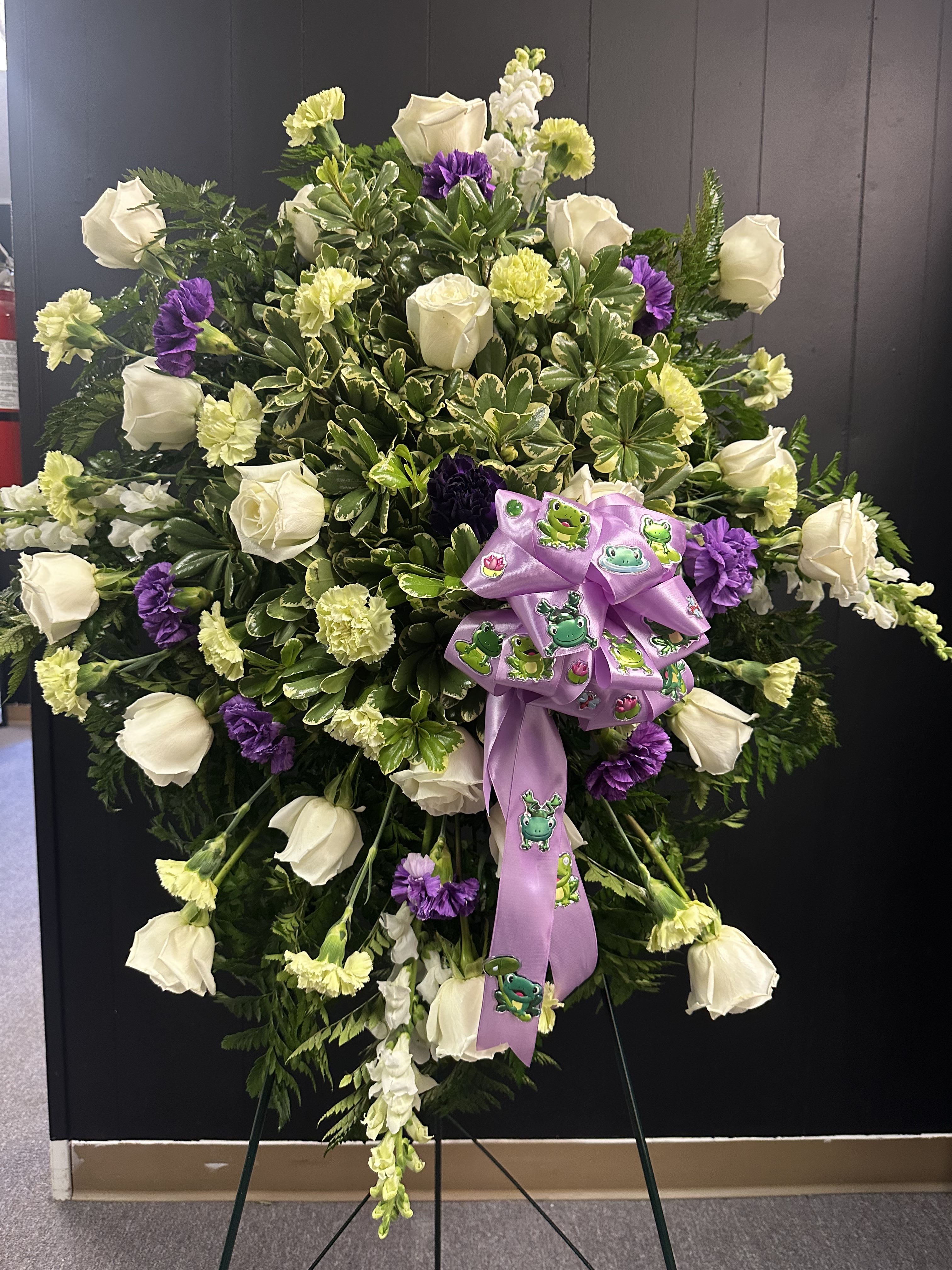 Leap of Faith - This frog-inspired funeral spray is a beautiful way to show one’s love of frogs and favorite colors.  Includes: white roses, purple &amp; light green carnations, white snapdragons, and greenery.
