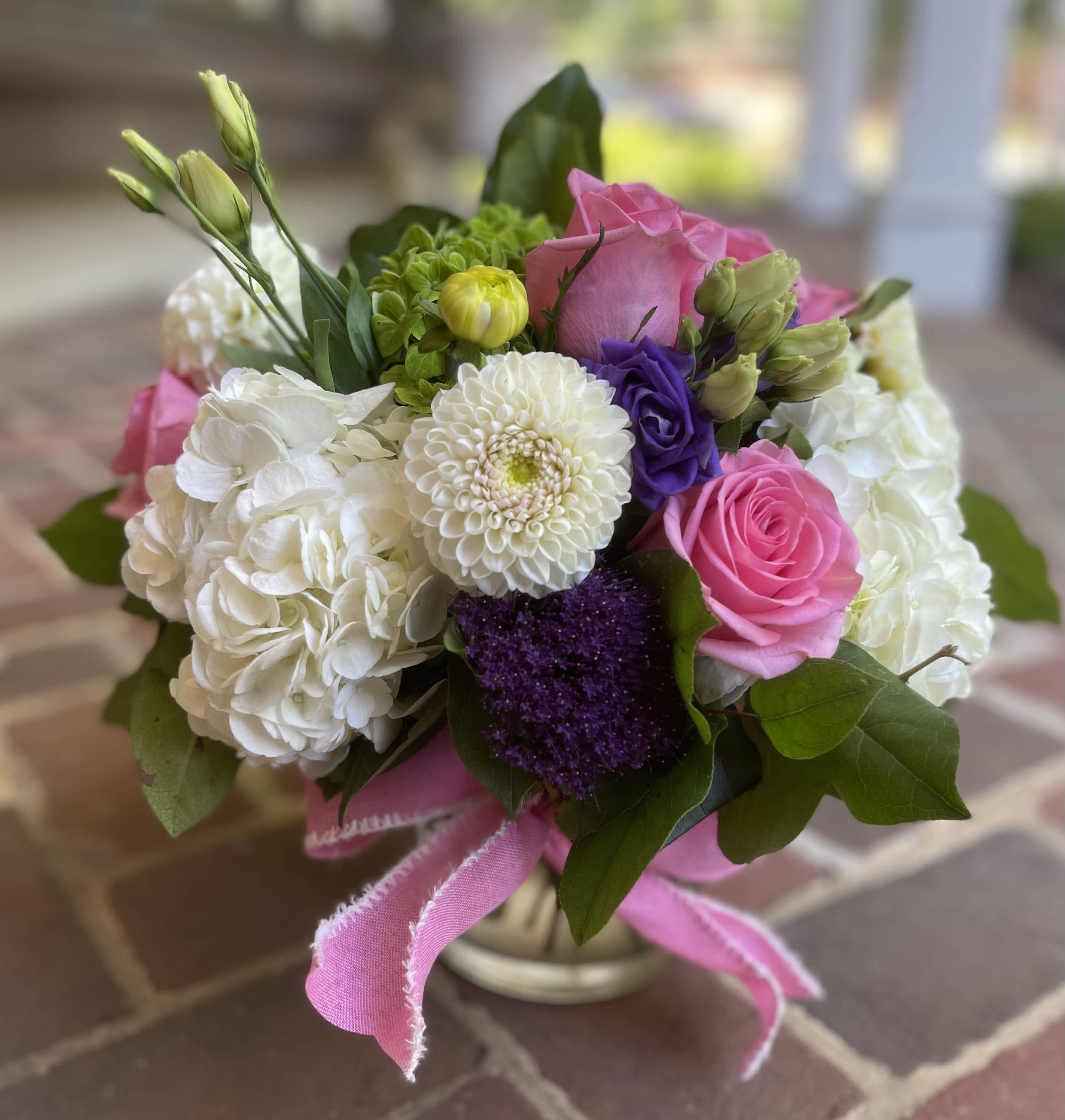 Bouquet of pink and white flowers in a small vase with a pink ribbon