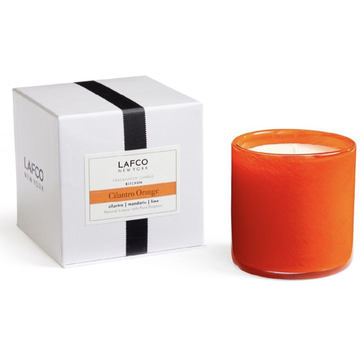 Orange candle in a glass jar beside a white gift box