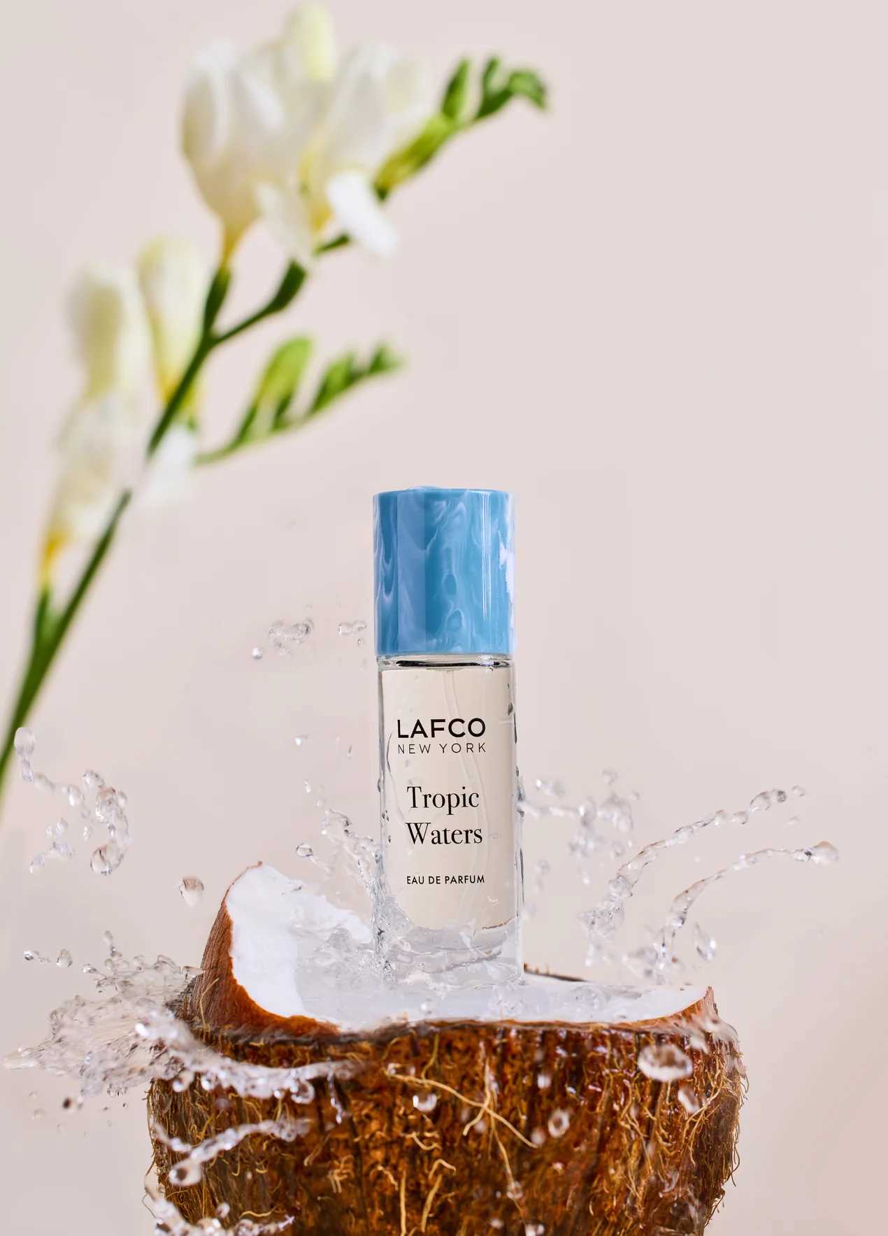 Perfume bottle on a coconut half with water splashing around it