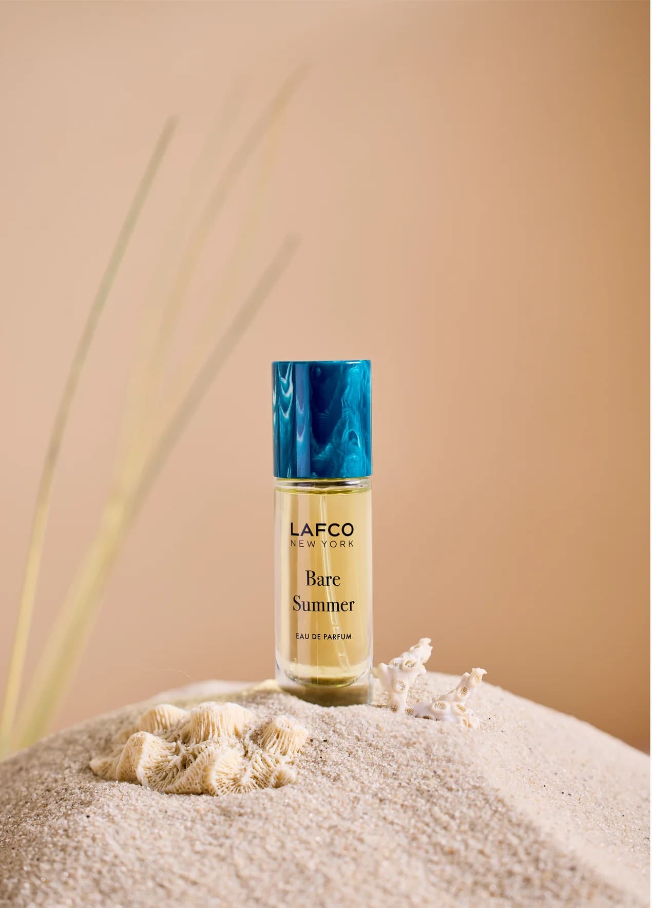 Bottle of LAFCO New York Bare Summer perfume on sand with seashells