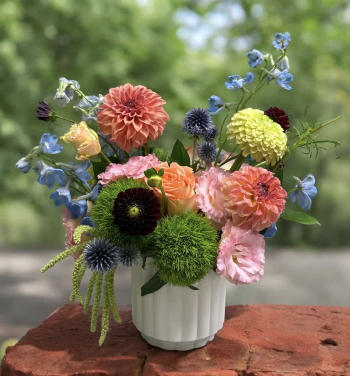 Colorful mixed bouquet in a white vase with dahlias and other blooms