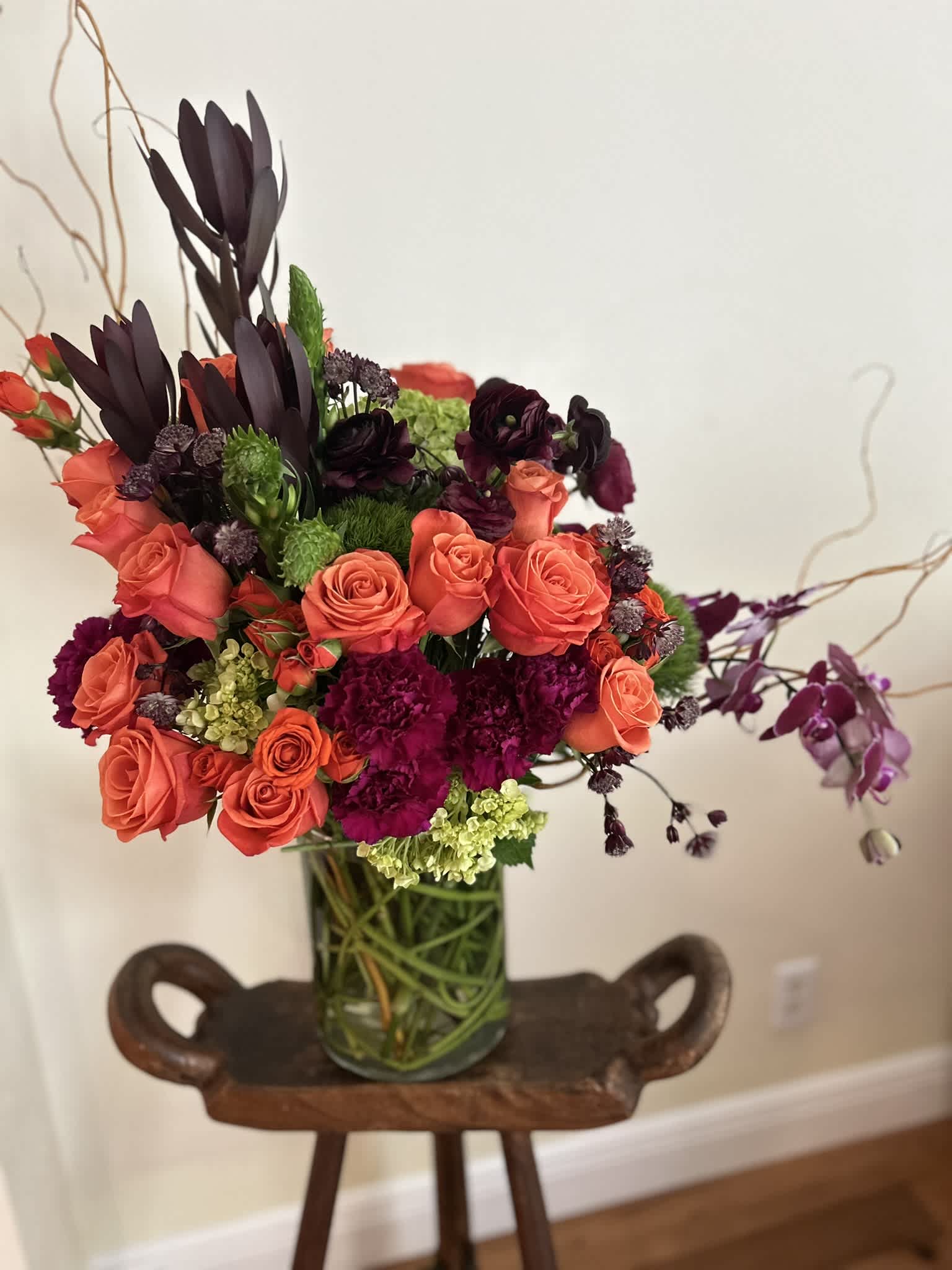 Coral roses and dark purple flowers arranged in a glass vase