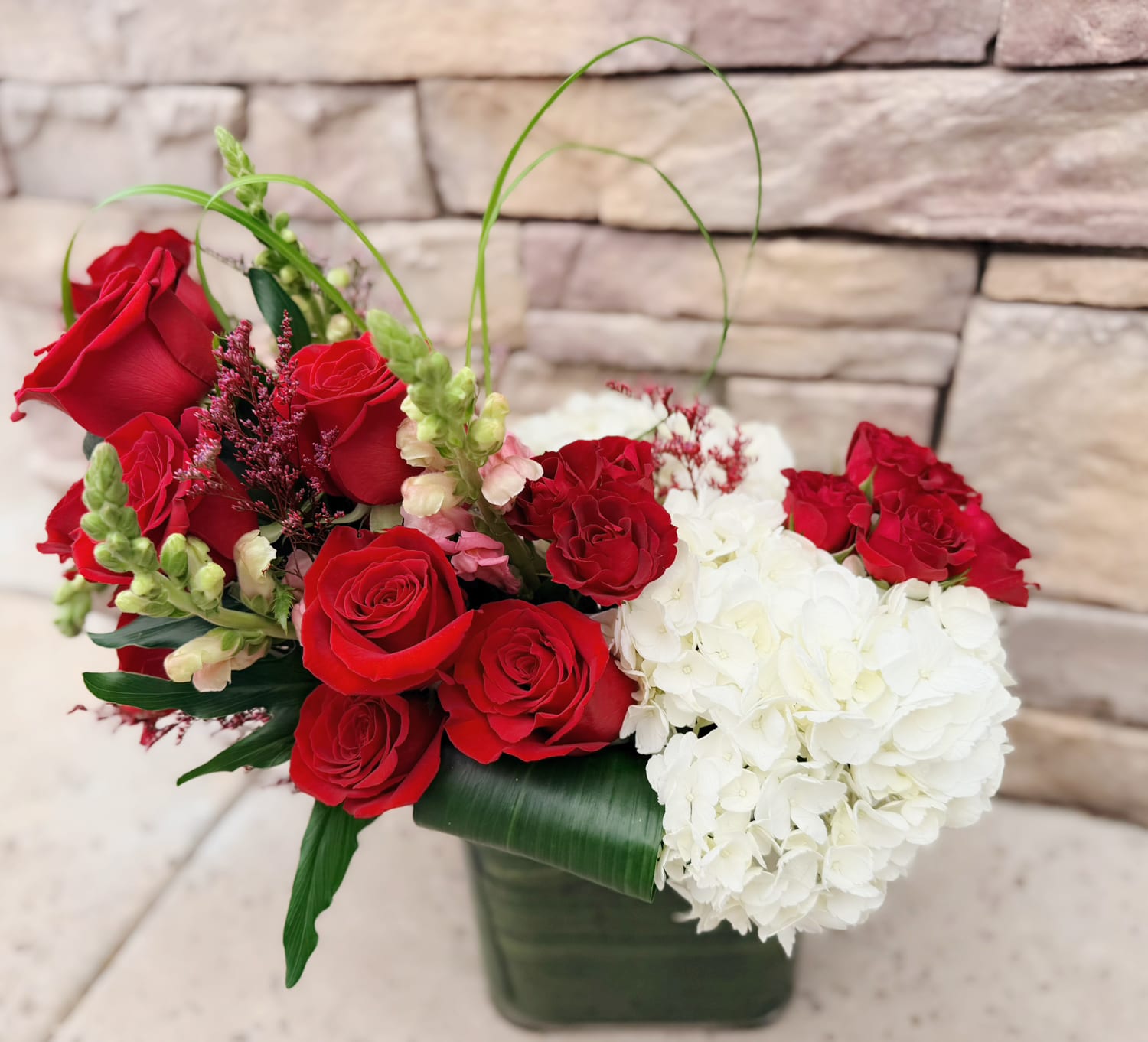 Red roses and white hydrangeas in a square vase