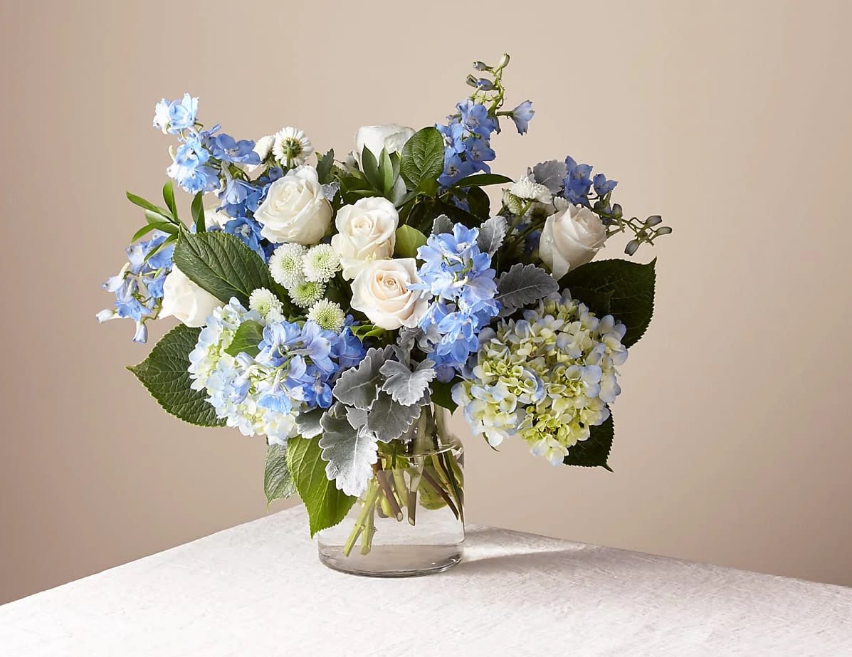 Blue and white bouquet of roses and hydrangeas in a glass vase