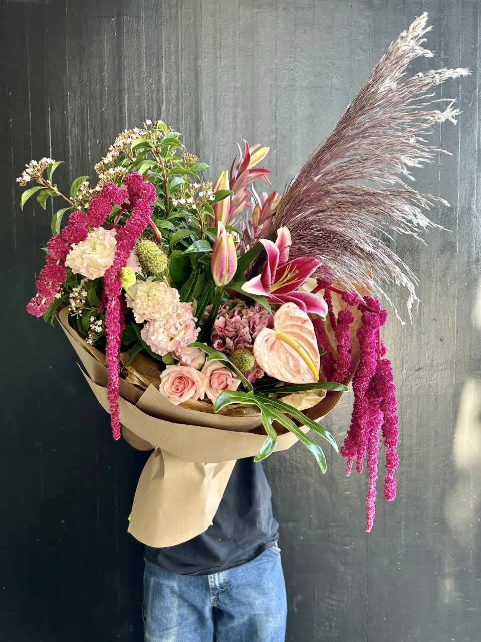 Large bouquet with pink lilies, roses, and pampas grass wrapped in paper