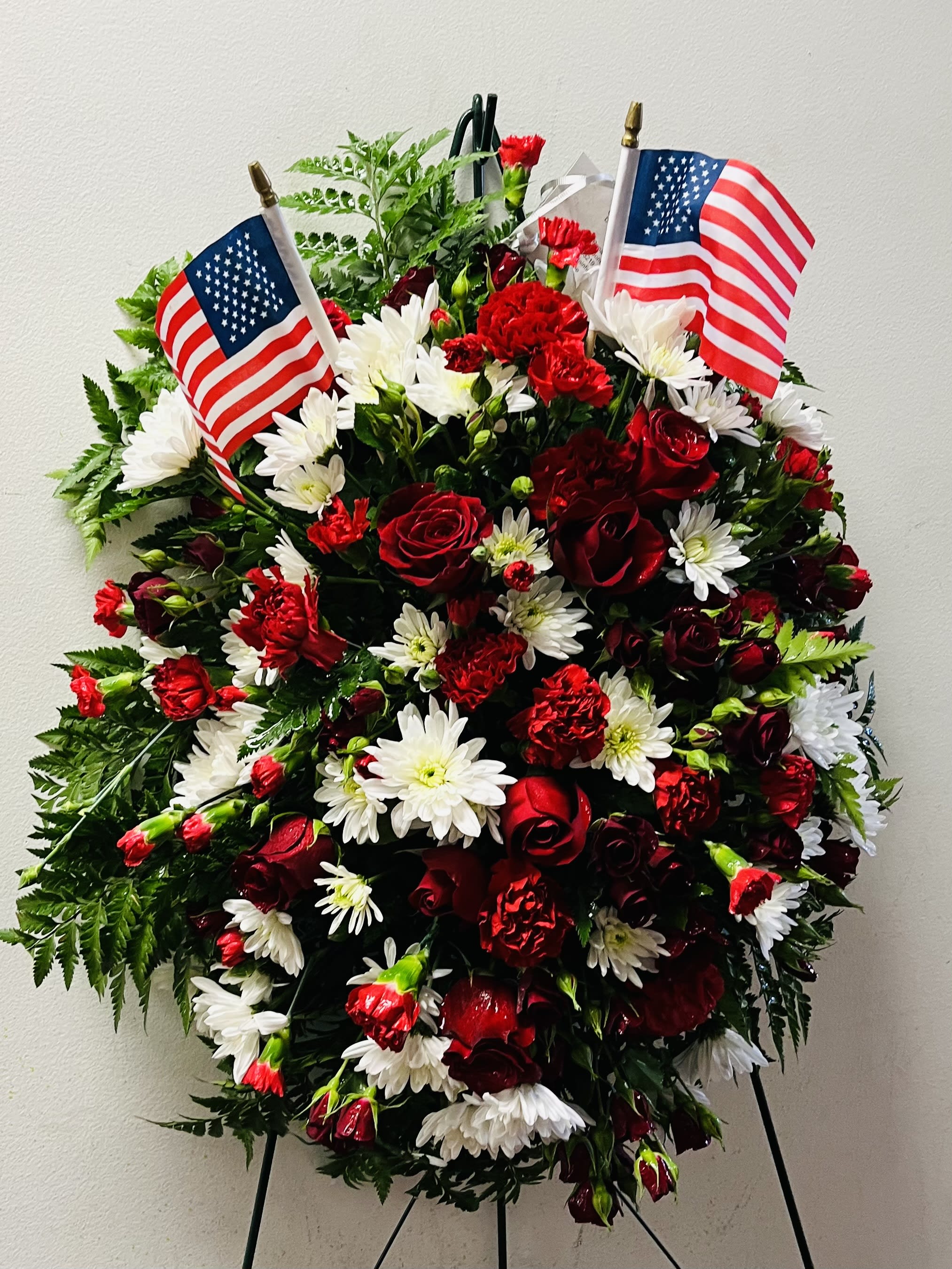 Red and white floral standing wreath with two American flags