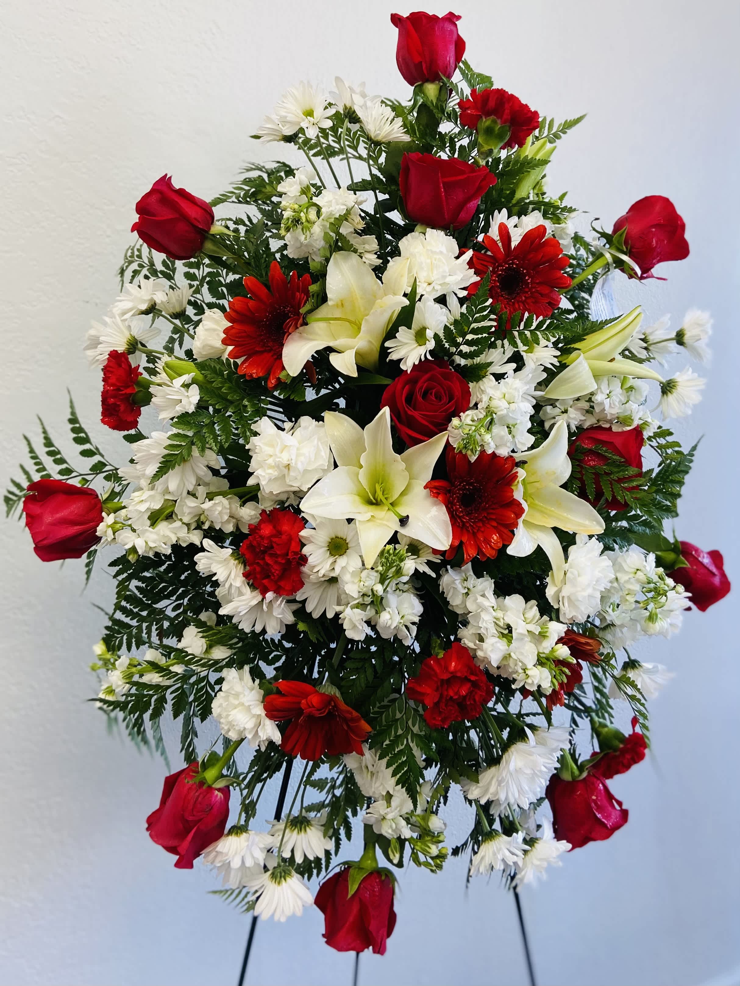 Standing floral spray with red roses, white lilies, and red and white daisies