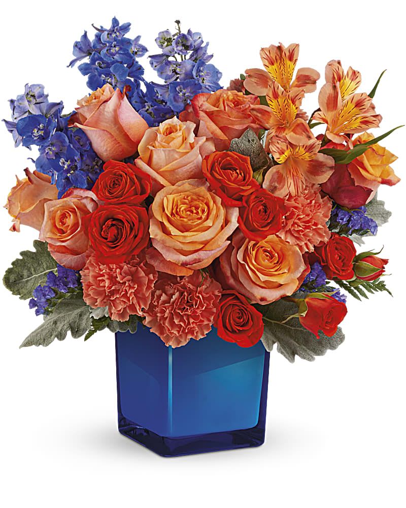 Bouquet of roses, carnations, and blue flowers in a blue glass vase