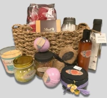 Basket of bath and body gift items with jars, bottles, and bath bombs