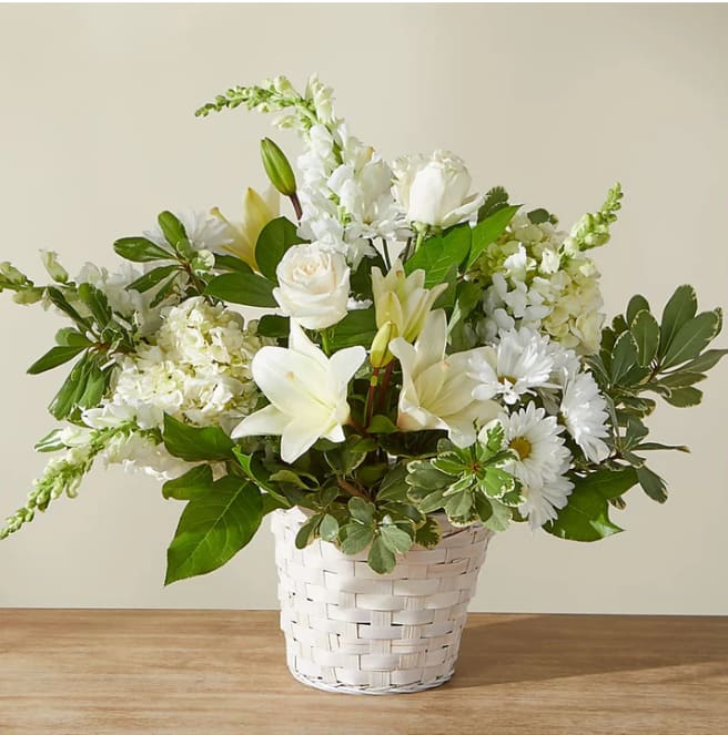 White floral arrangement in a white woven basket