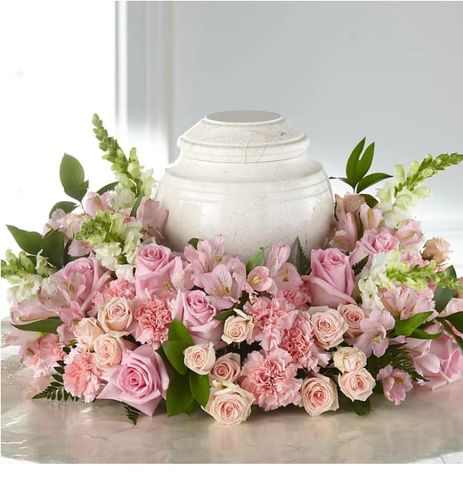 Pink roses and carnations arranged around a white urn