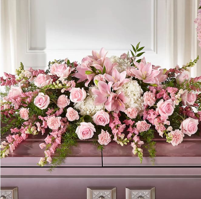 Pink roses and lilies arranged across a casket