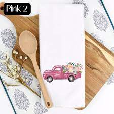 Pink truck graphic on a white towel with wooden spoon and cutting board