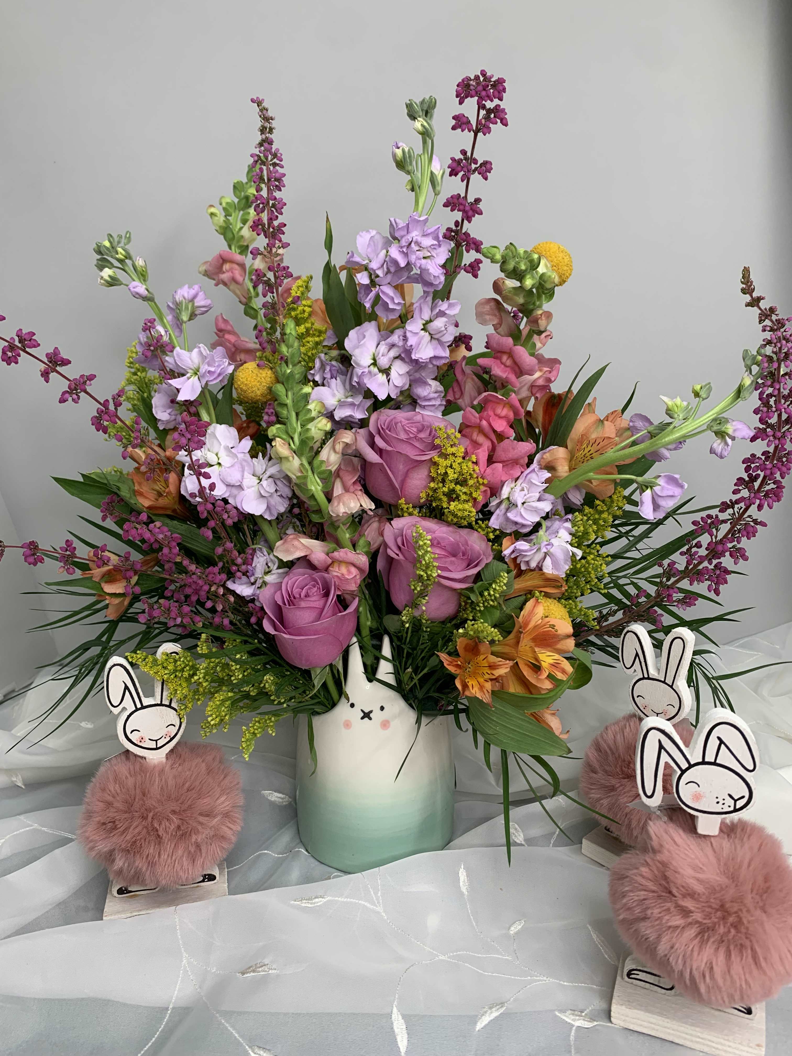 Mixed pink and purple bouquet in a ceramic vase with bunny decorations