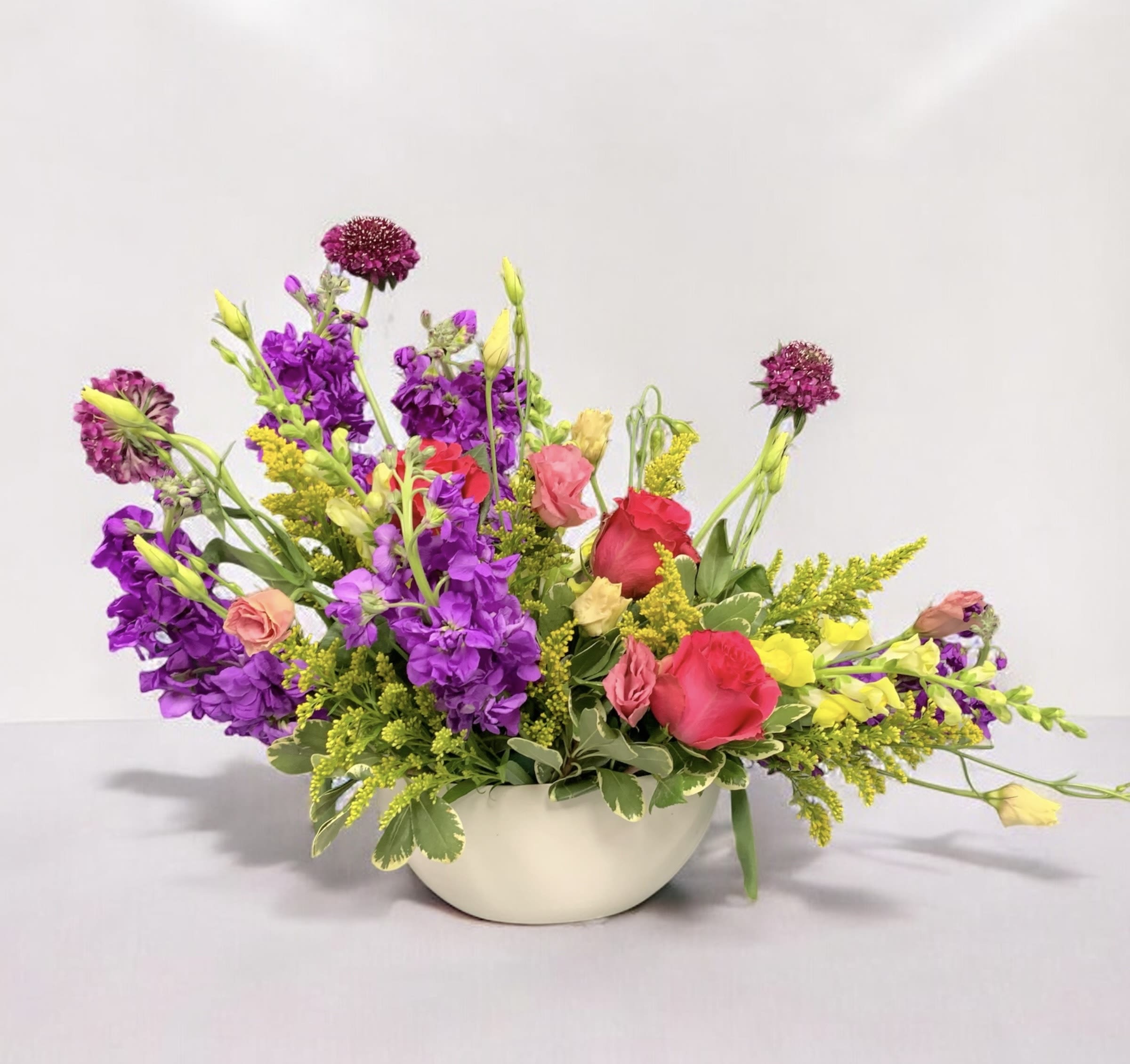 Colorful mixed flower arrangement in a white bowl vase