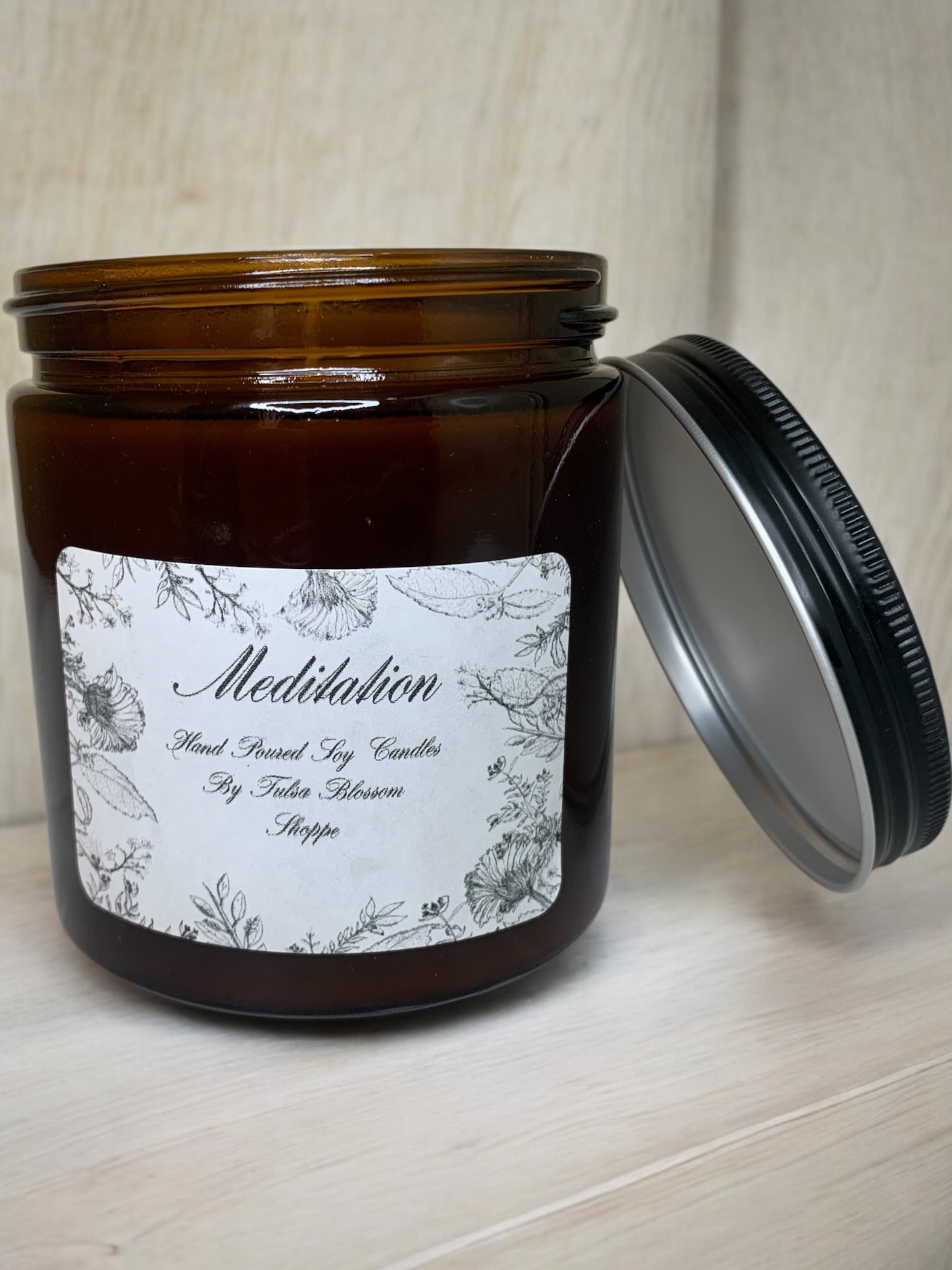Amber jar candle with a floral label and black lid