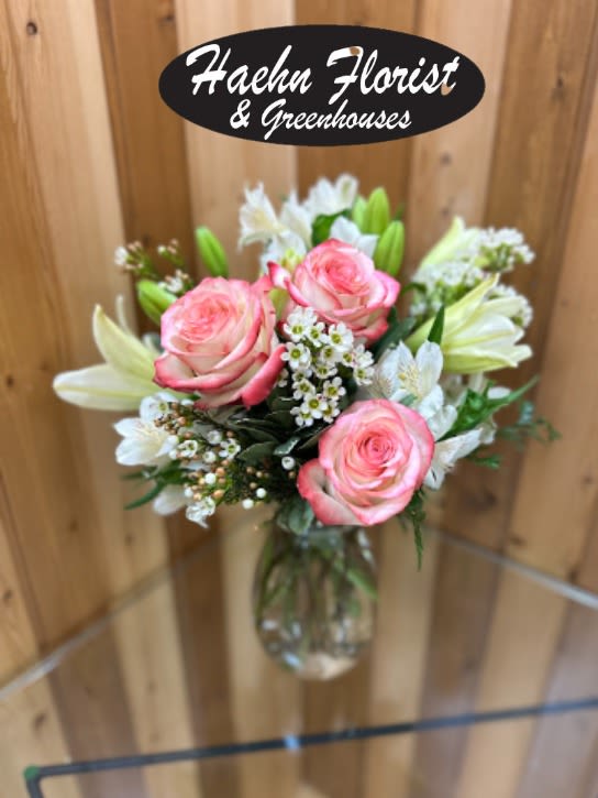Pink roses and white lilies in a clear glass vase