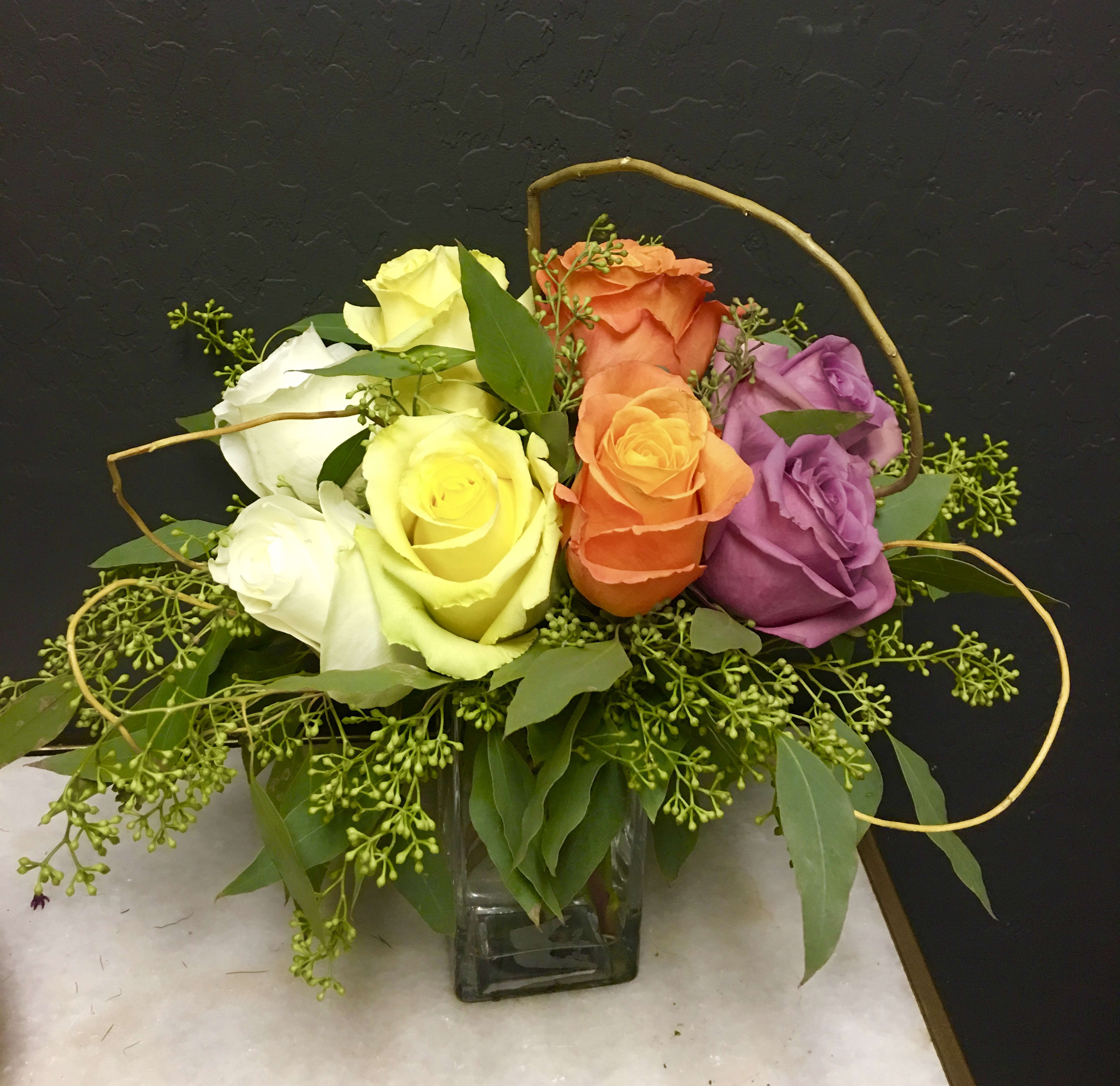 Colorful rose arrangement in a square glass vase
