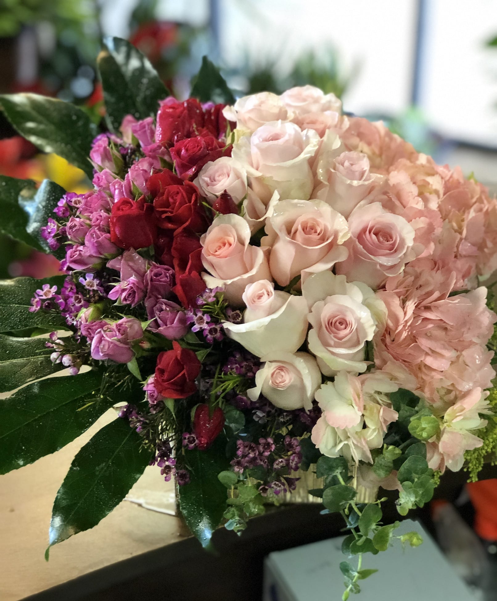 Bouquet of pink, red, and white roses with hydrangea and greenery