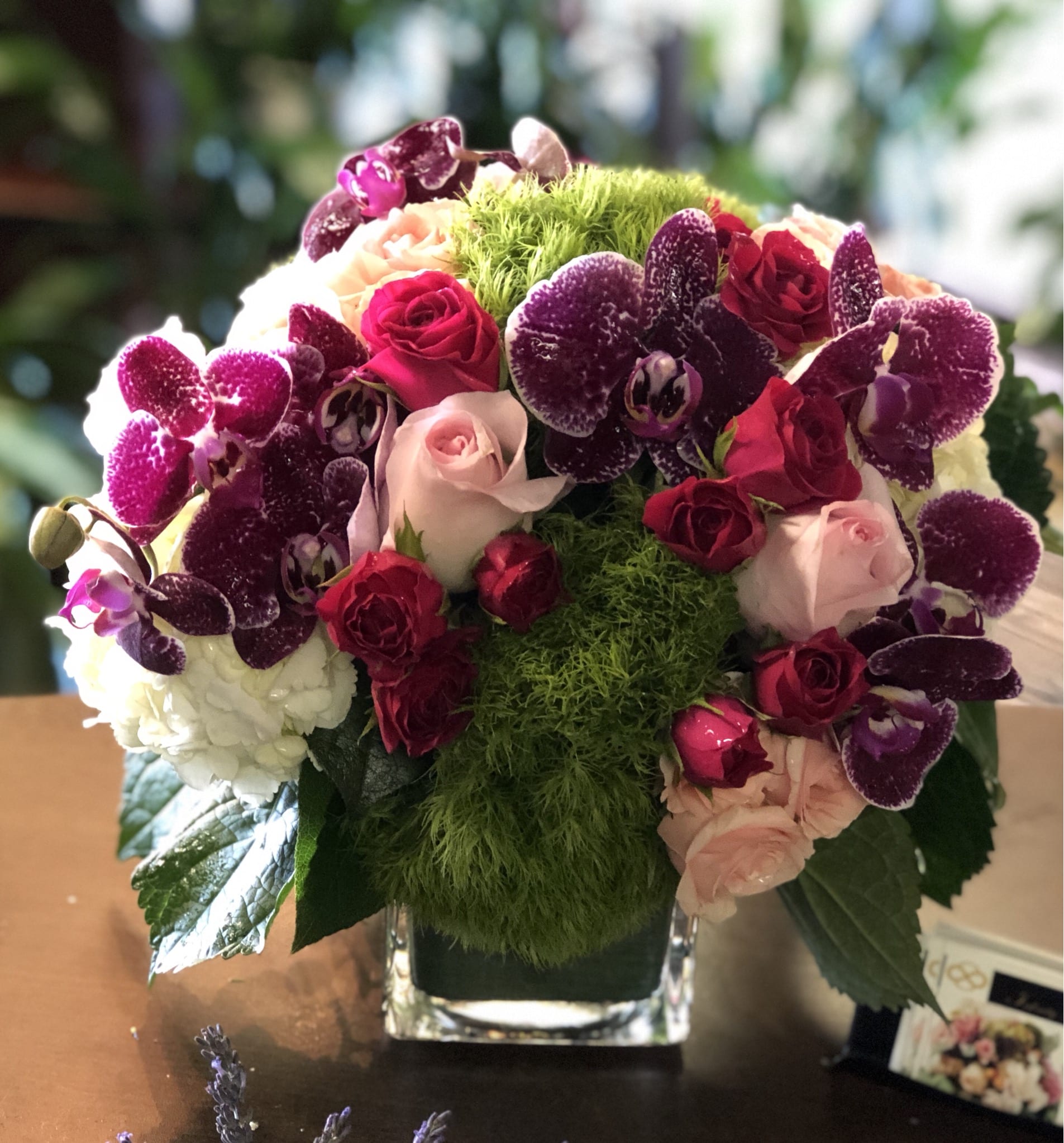 Bouquet of pink and red roses with purple orchids in a glass vase