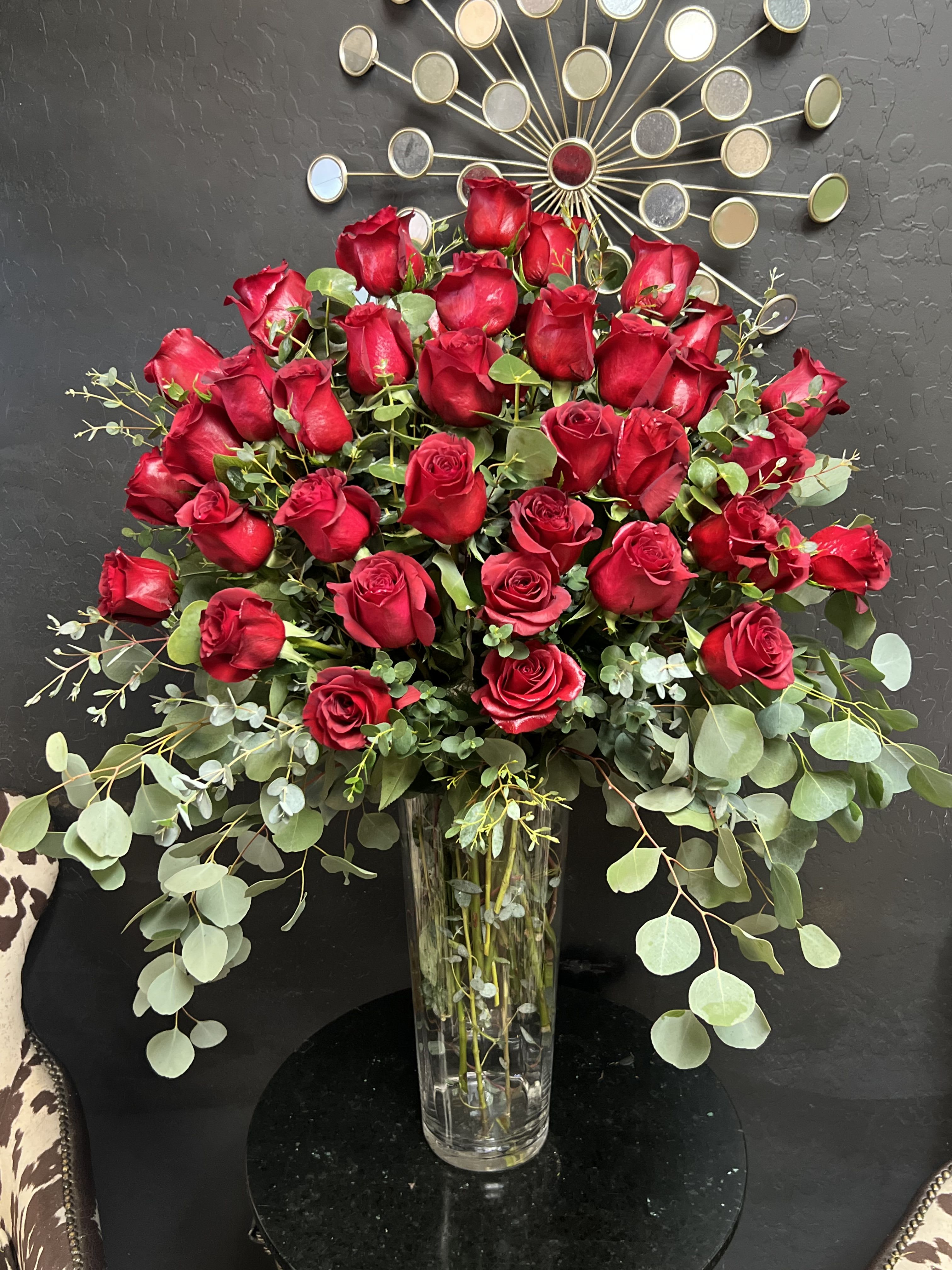 Tall vase arrangement of red roses with eucalyptus