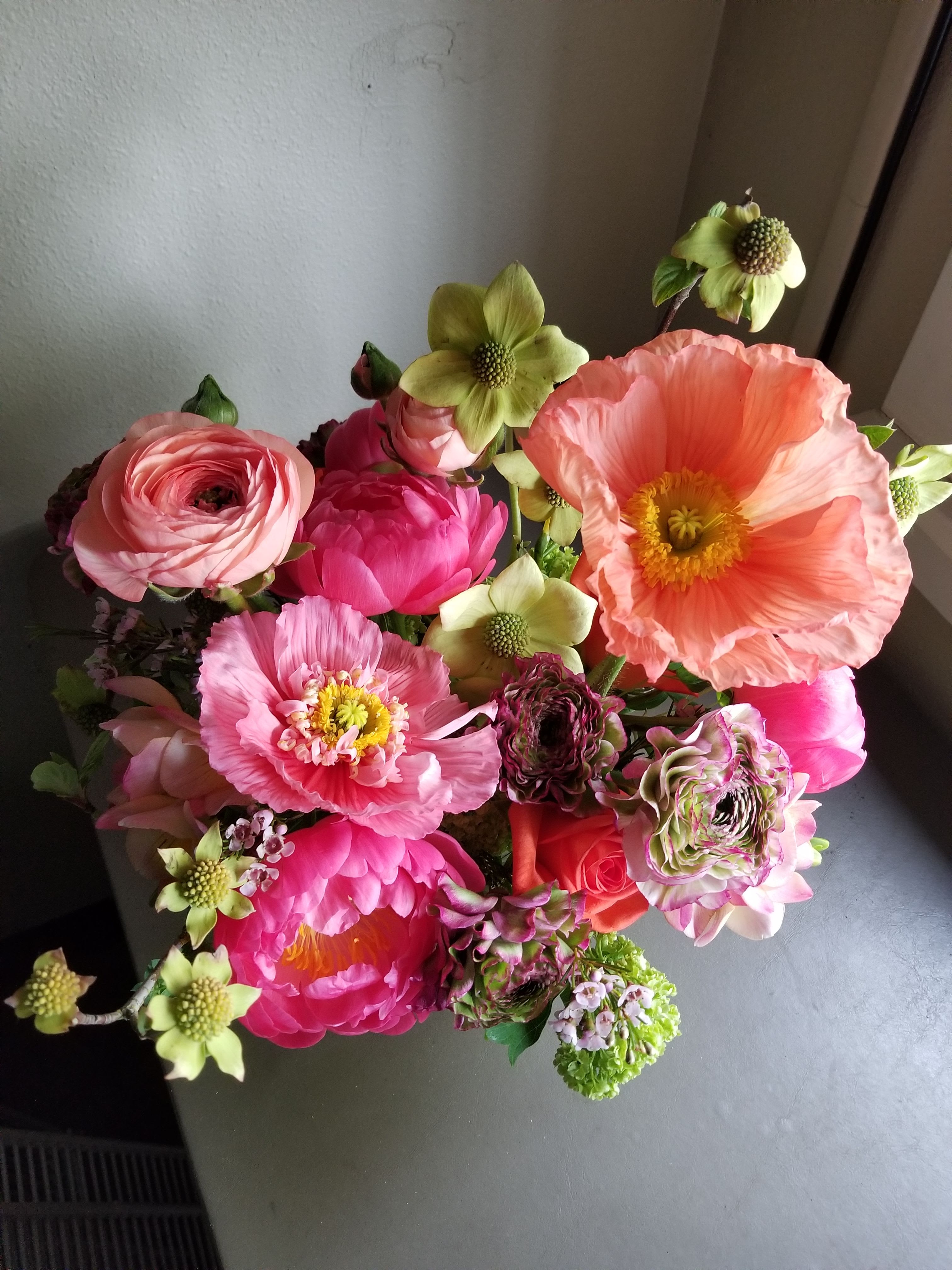 Top view of a bright pink and peach flower arrangement with large poppies and ranunculus