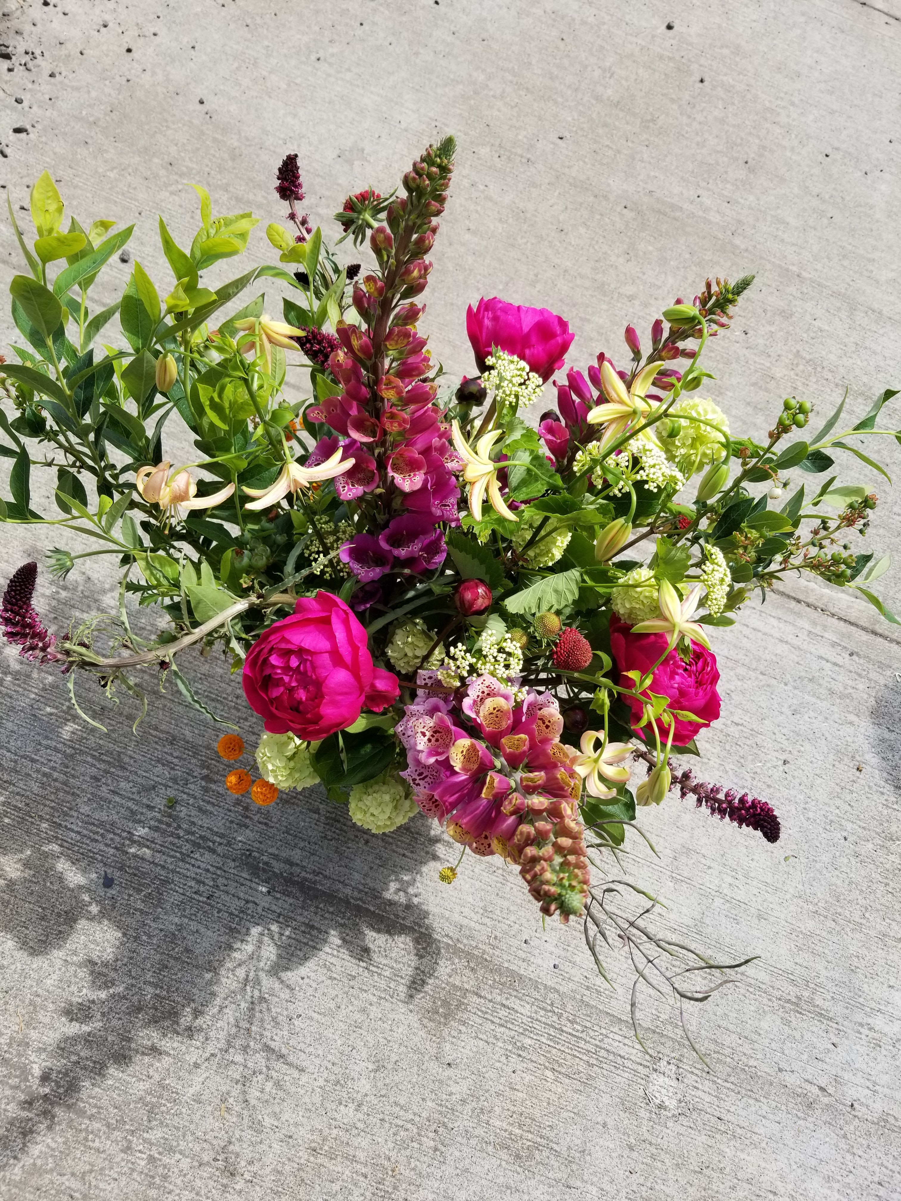 Loose arrangement of bright pink and mixed flowers in a low design on a concrete surface