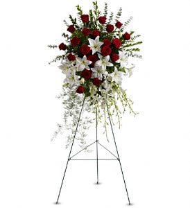 Standing floral spray with red roses and white lilies on an easel