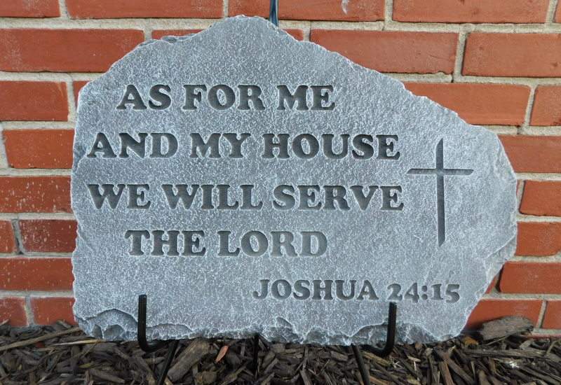 Engraved stone plaque with a Bible verse and cross against a brick wall