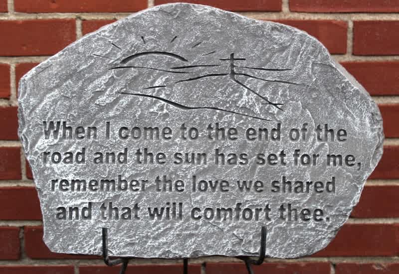 Engraved memorial stone with a quote against a brick wall.