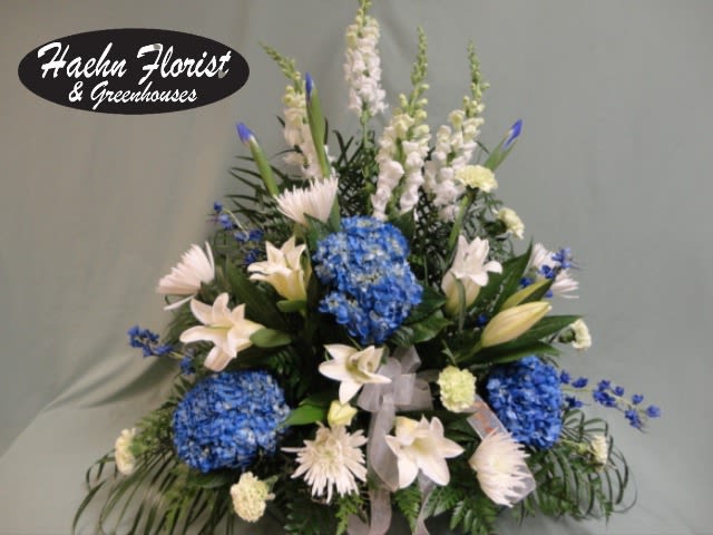 Blue hydrangeas and white lilies in a tall floral arrangement