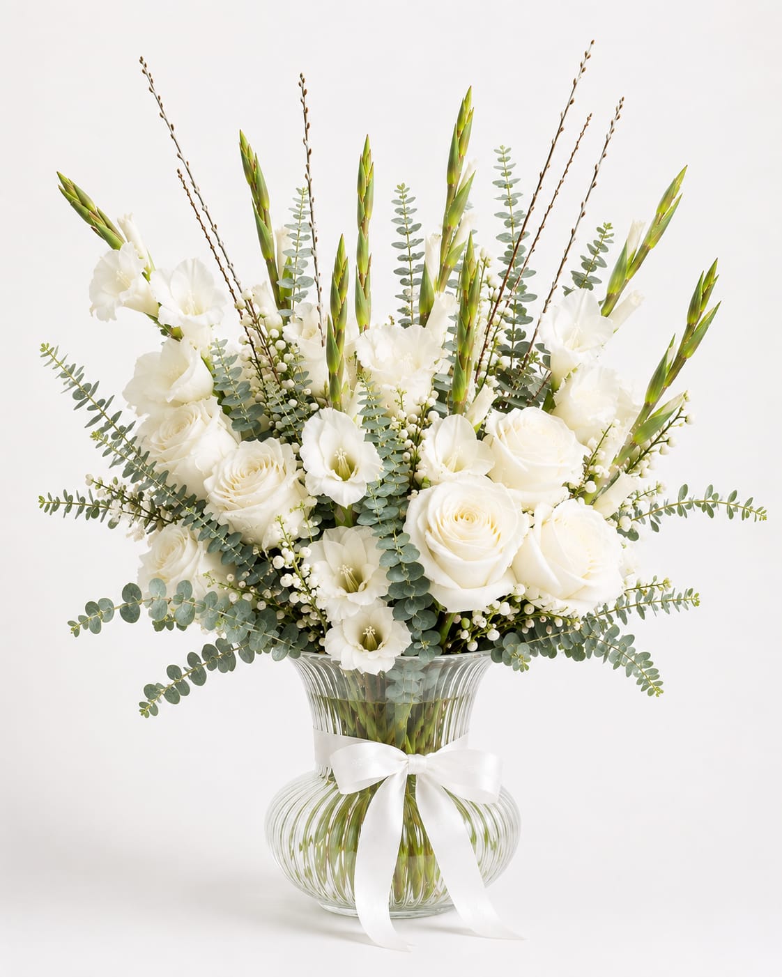 White roses and lilies in a clear glass vase with a white ribbon