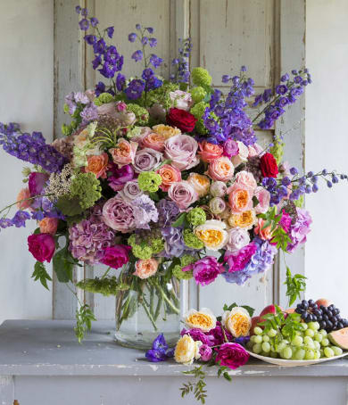Large mixed bouquet of roses and purple flowers in a glass vase