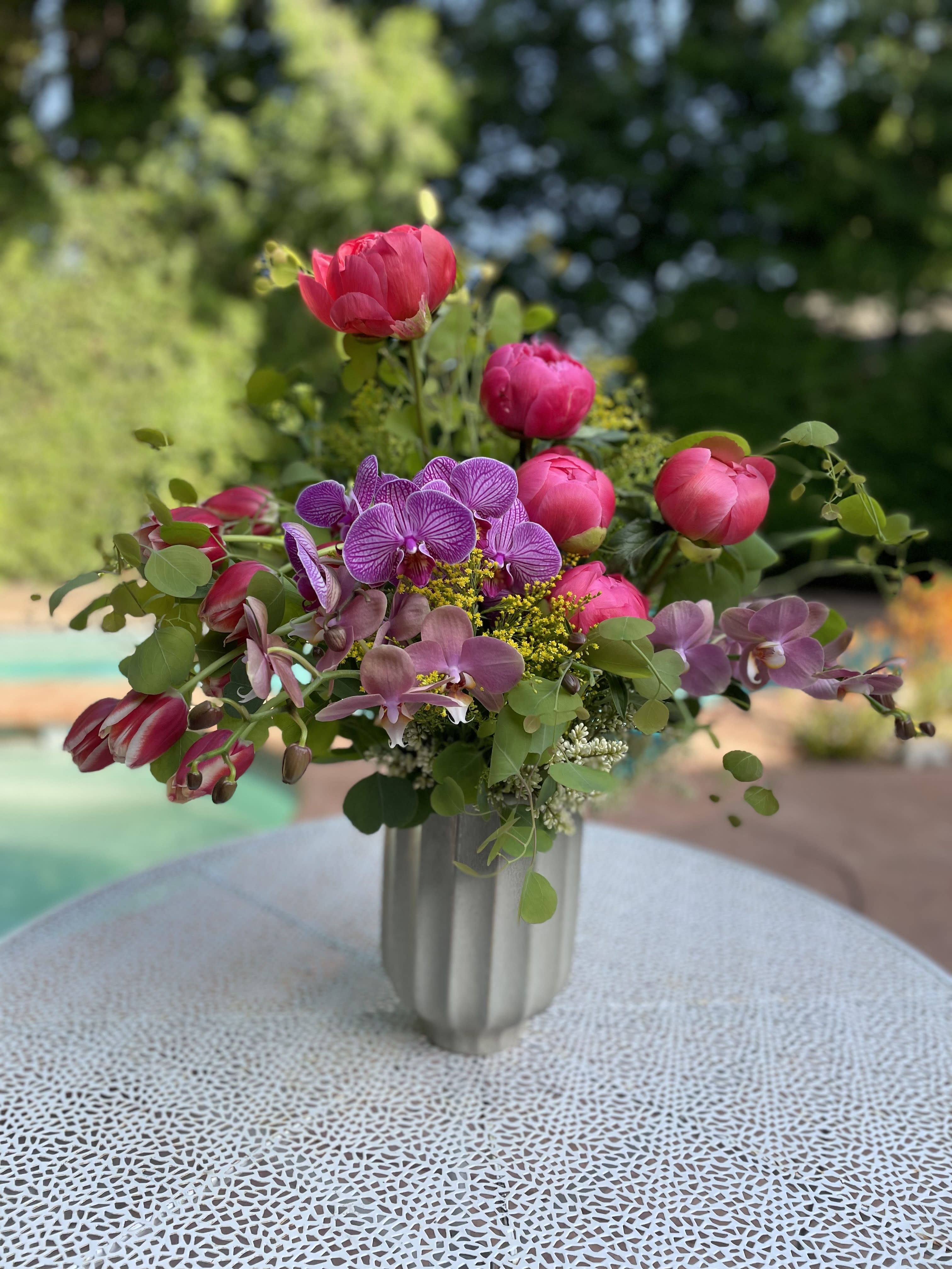 Pink and purple flowers arranged in a silver vase
