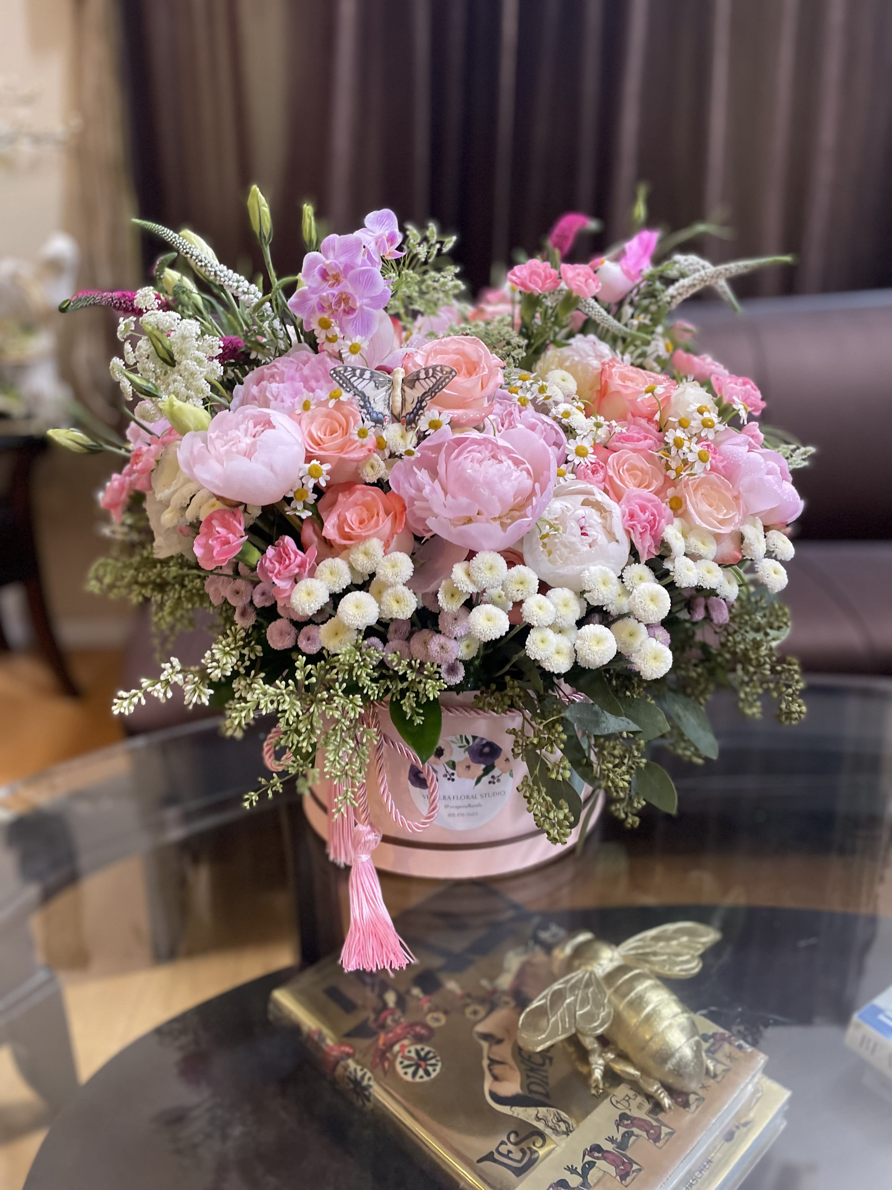 Pink mixed flower arrangement in a round hatbox with a tassel