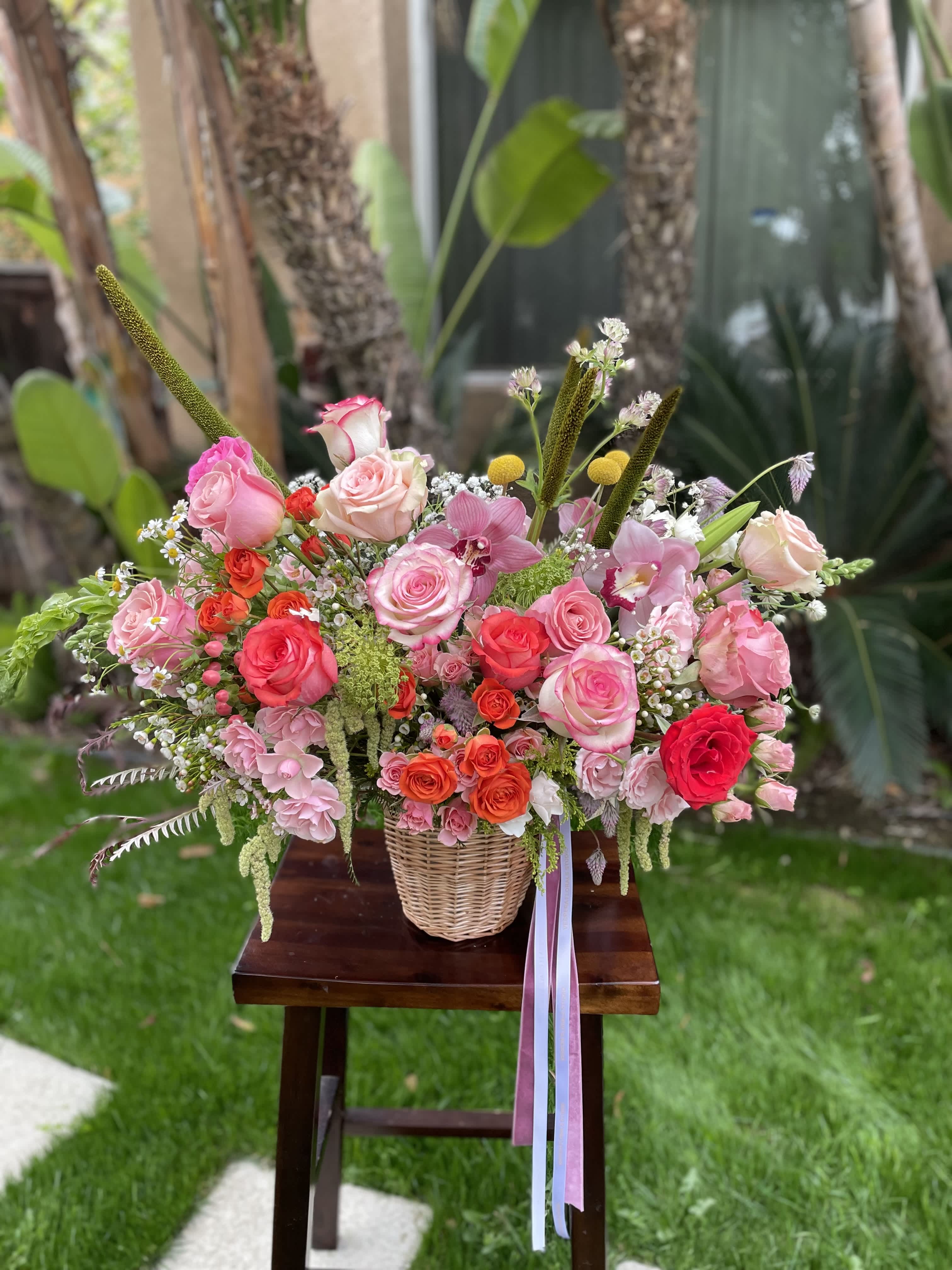 Mixed pink and coral rose arrangement in a wicker basket