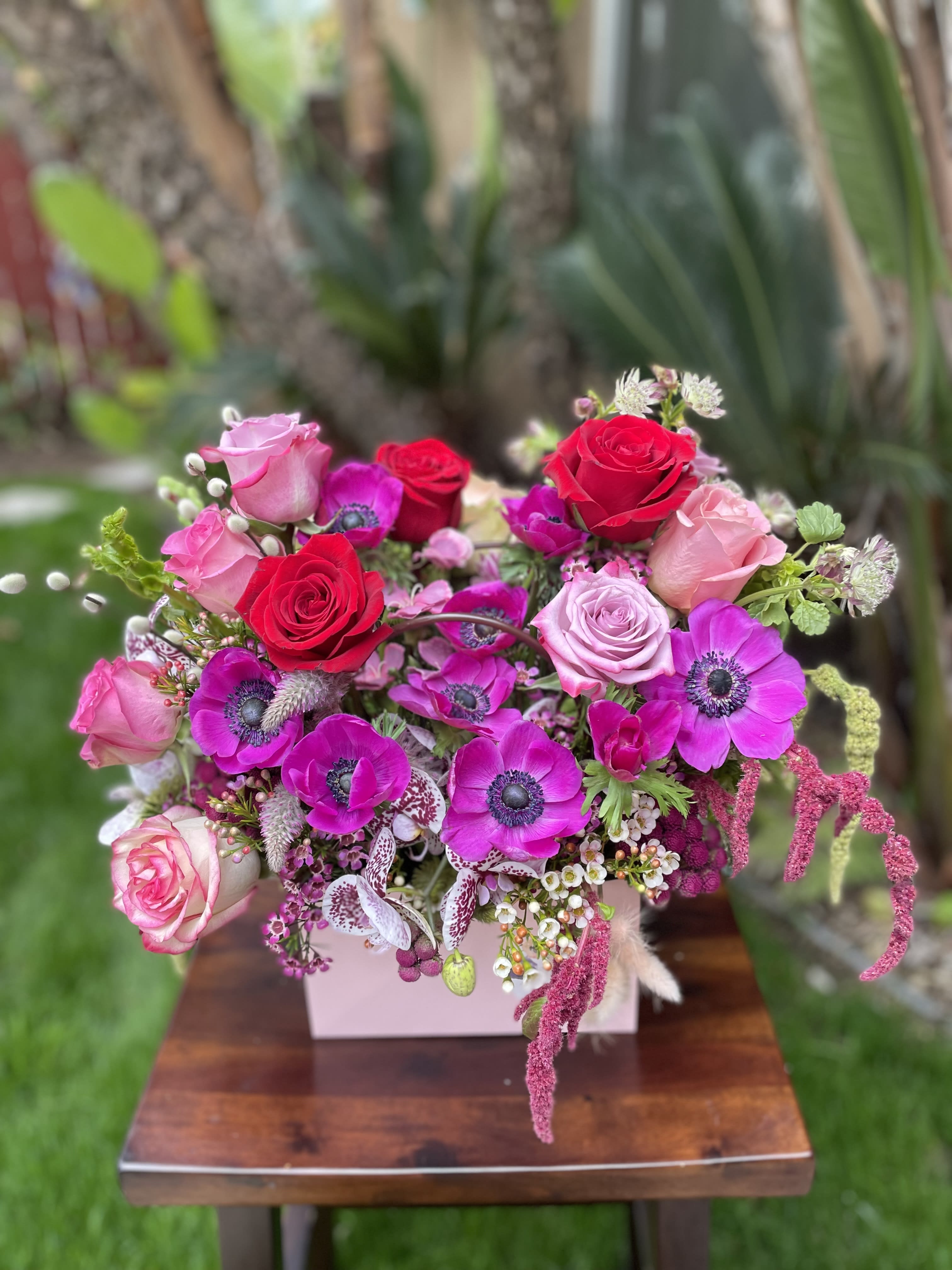 Pink and red rose bouquet with magenta anemones in a pale box