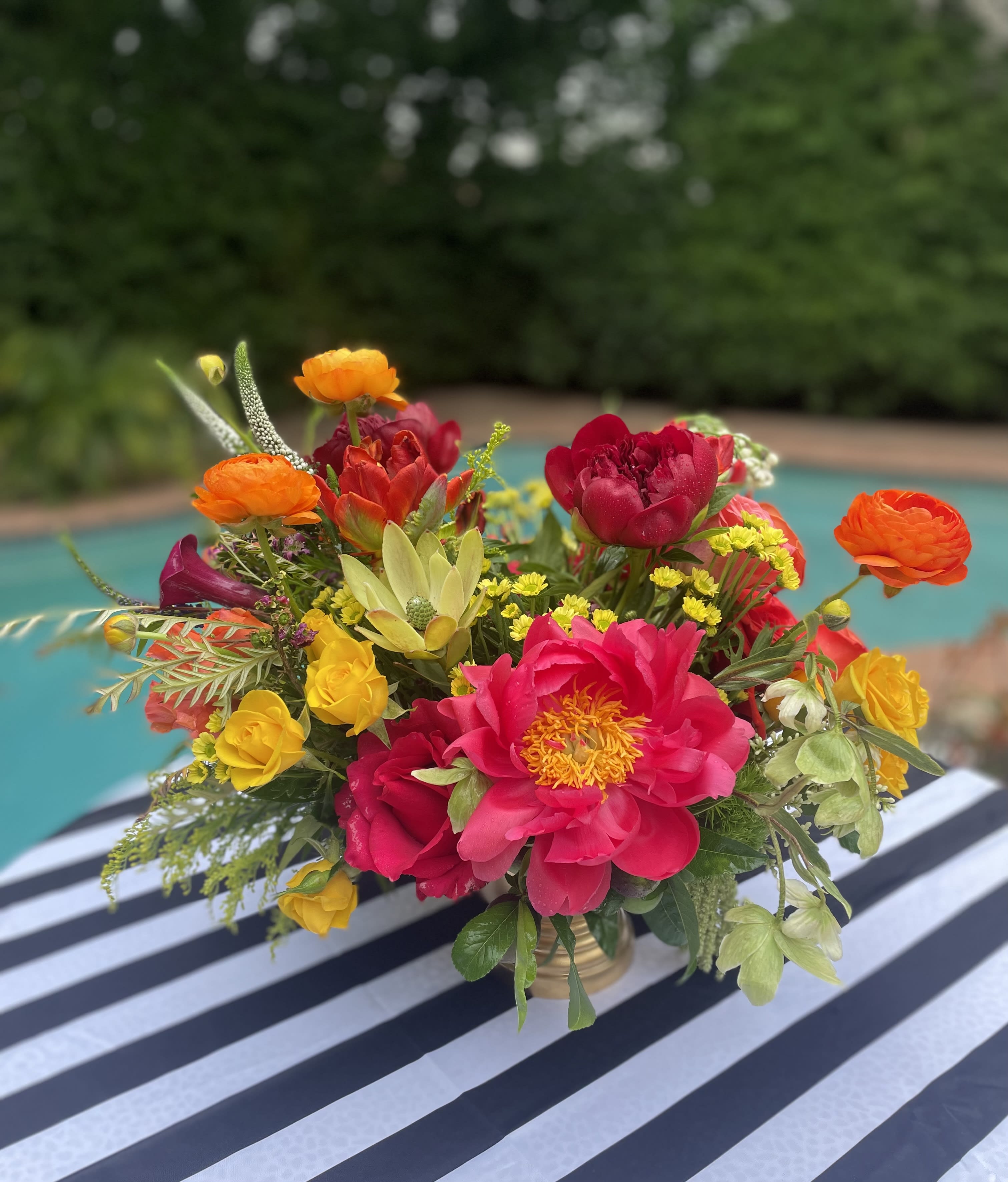 Bright mixed bouquet in a gold vase with pink, orange, and yellow blooms