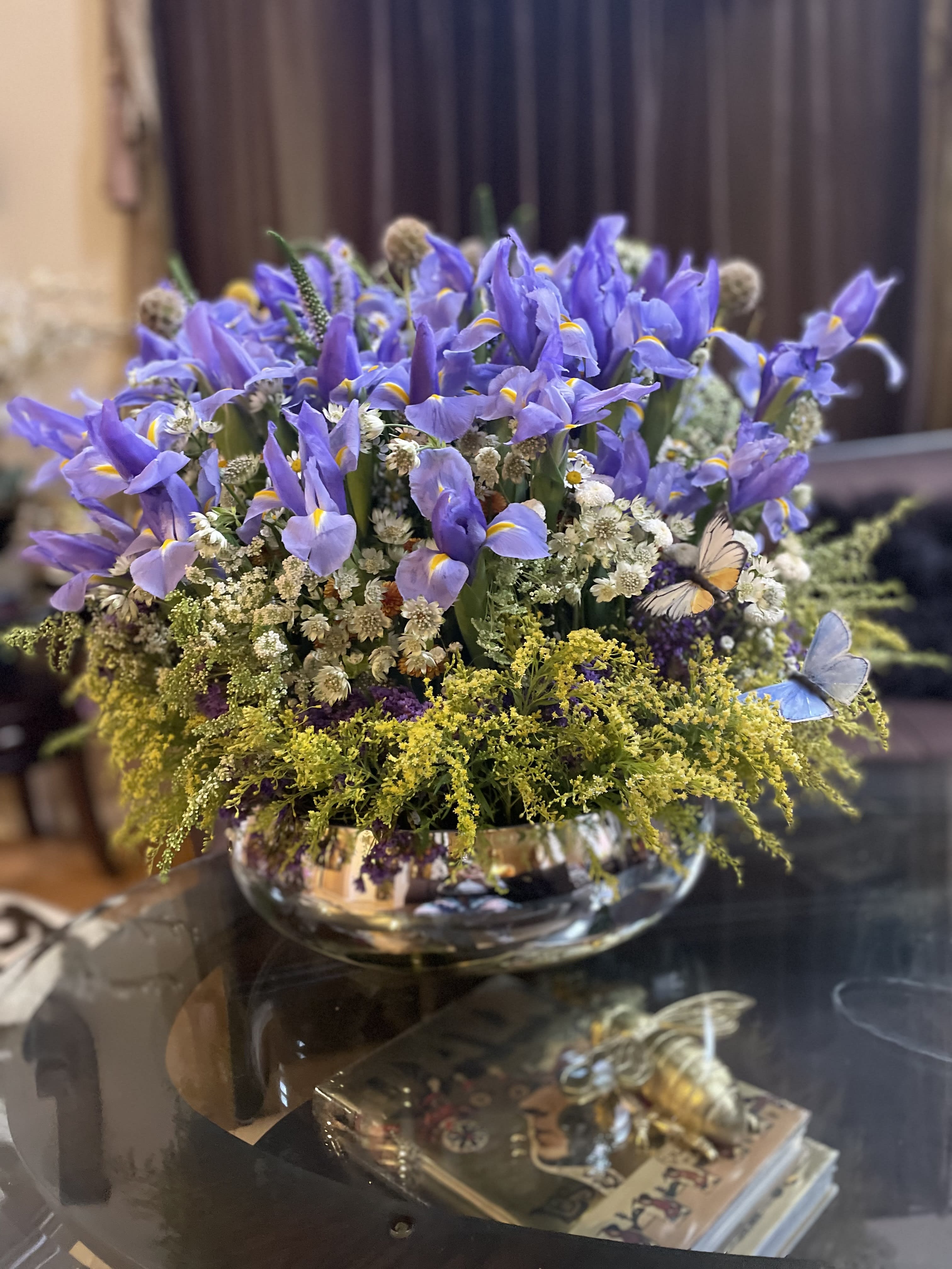 Purple iris arrangement in a low glass bowl with small white filler flowers