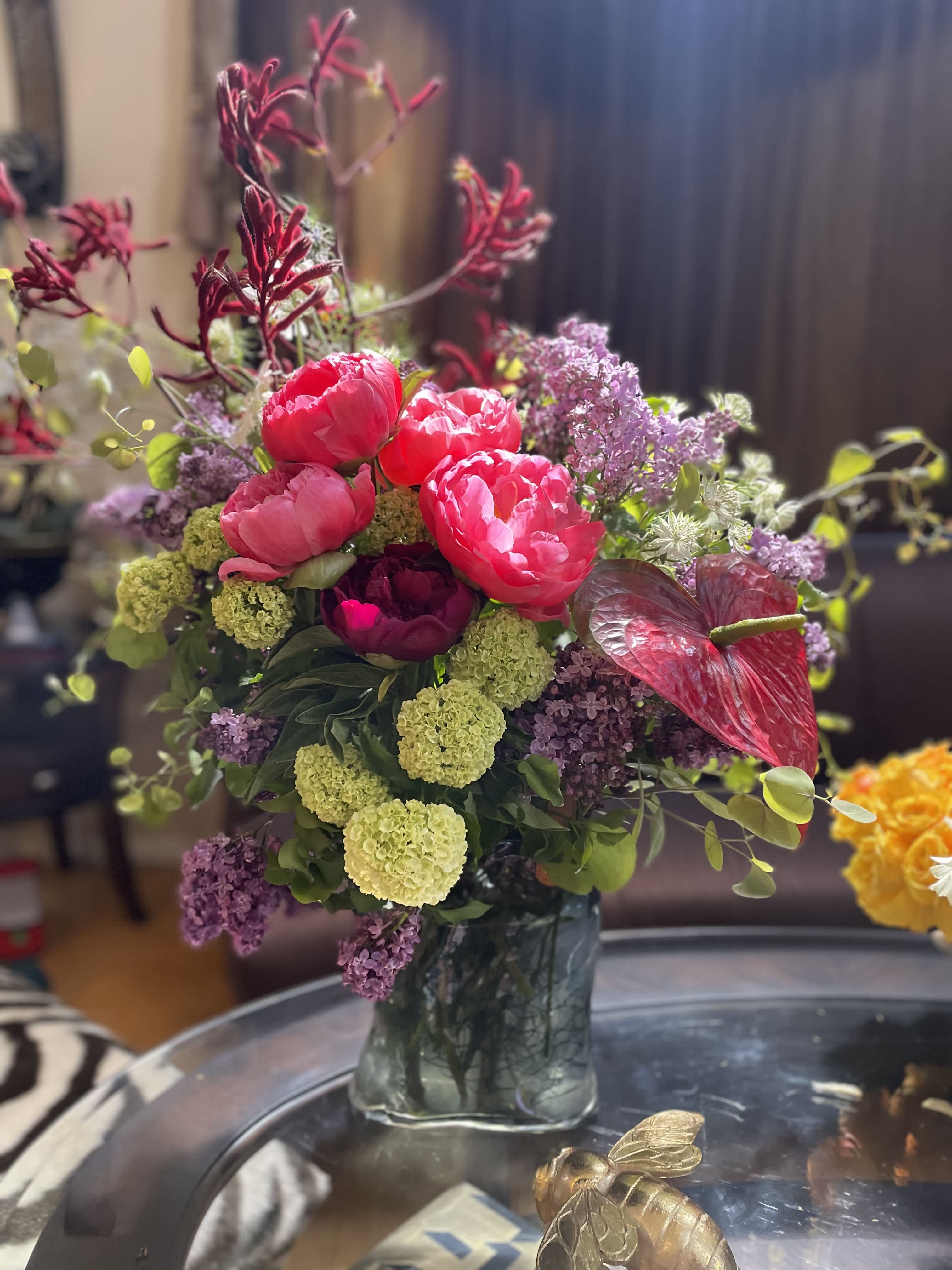 Pink peonies and purple flowers arranged in a glass vase