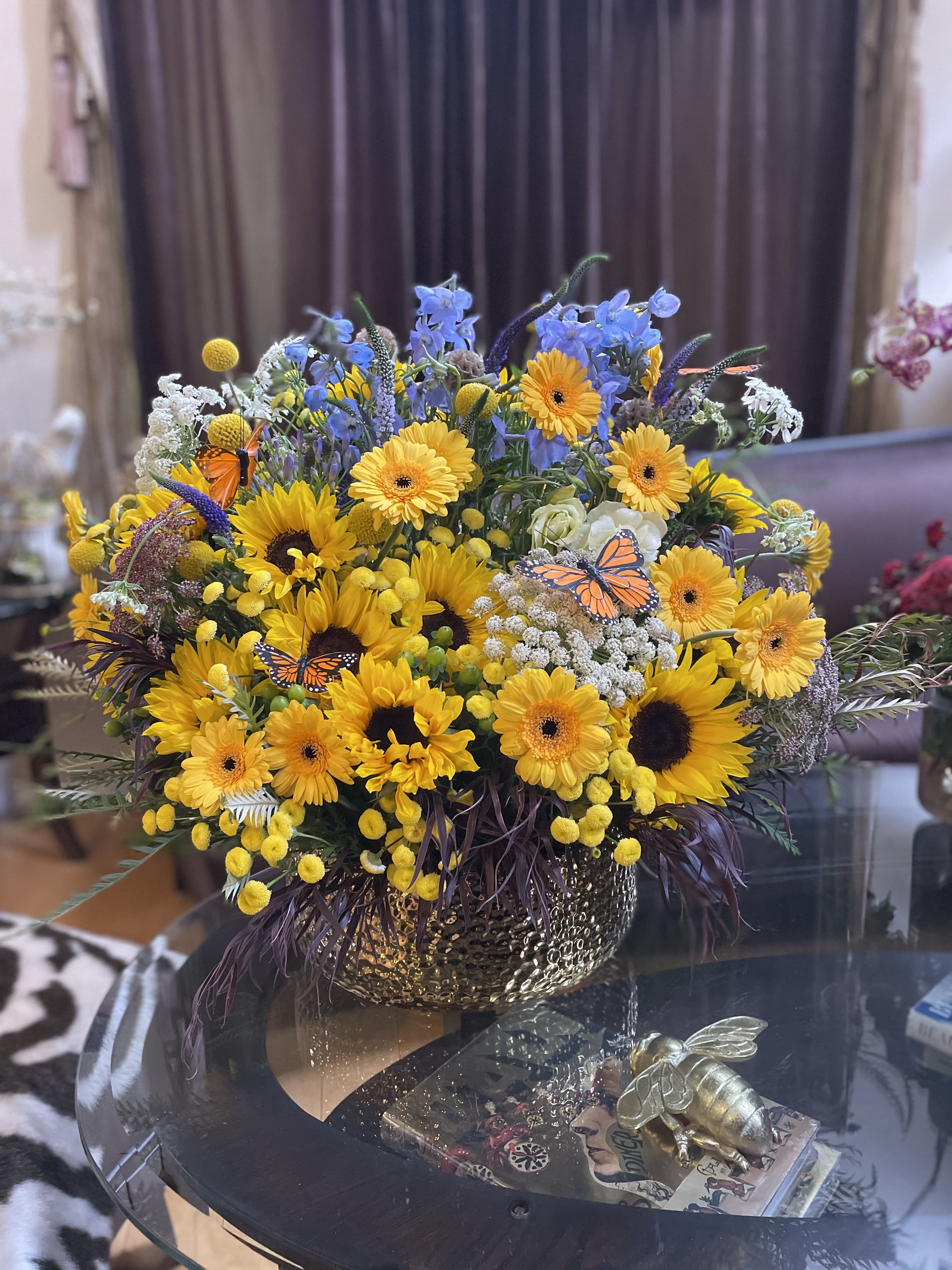 Mixed bouquet of yellow sunflowers and gerbera daisies in a gold vase