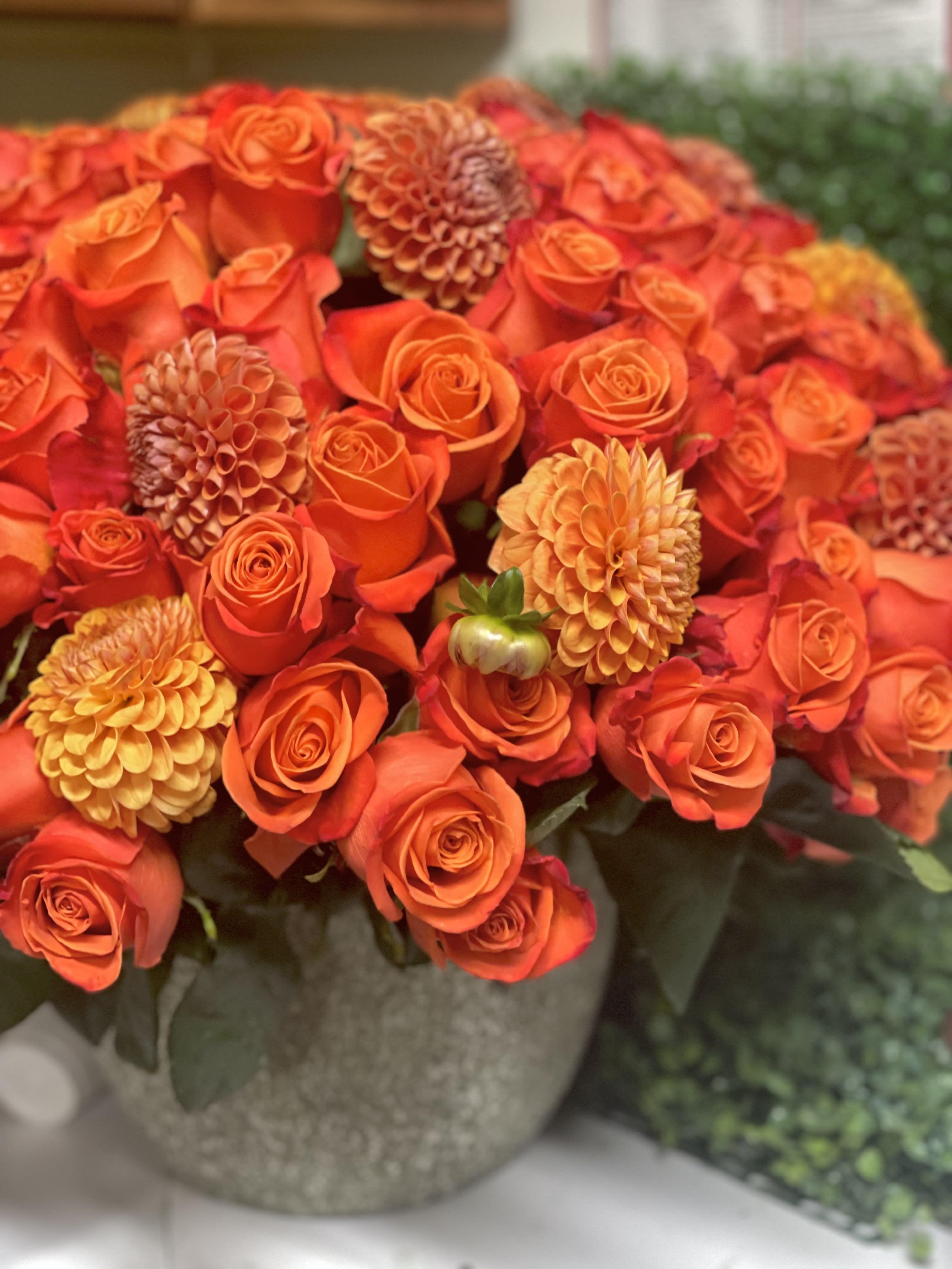 Orange roses and dahlias arranged in a round vase