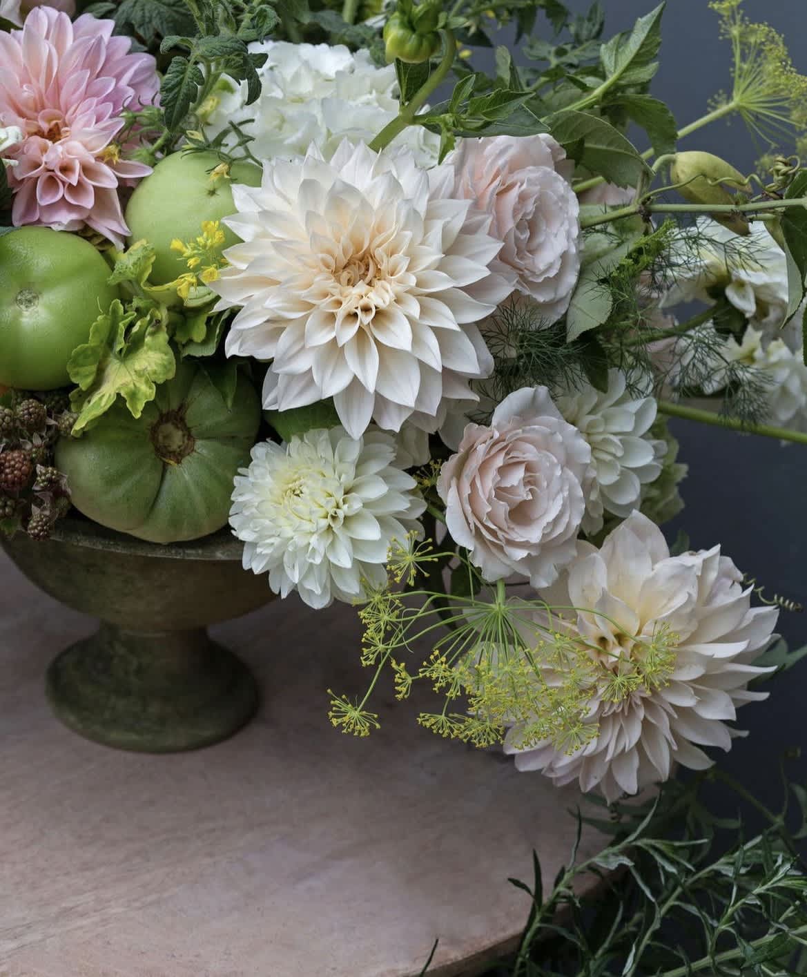 Arrangement of white and blush flowers with green fruit in a pedestal bowl