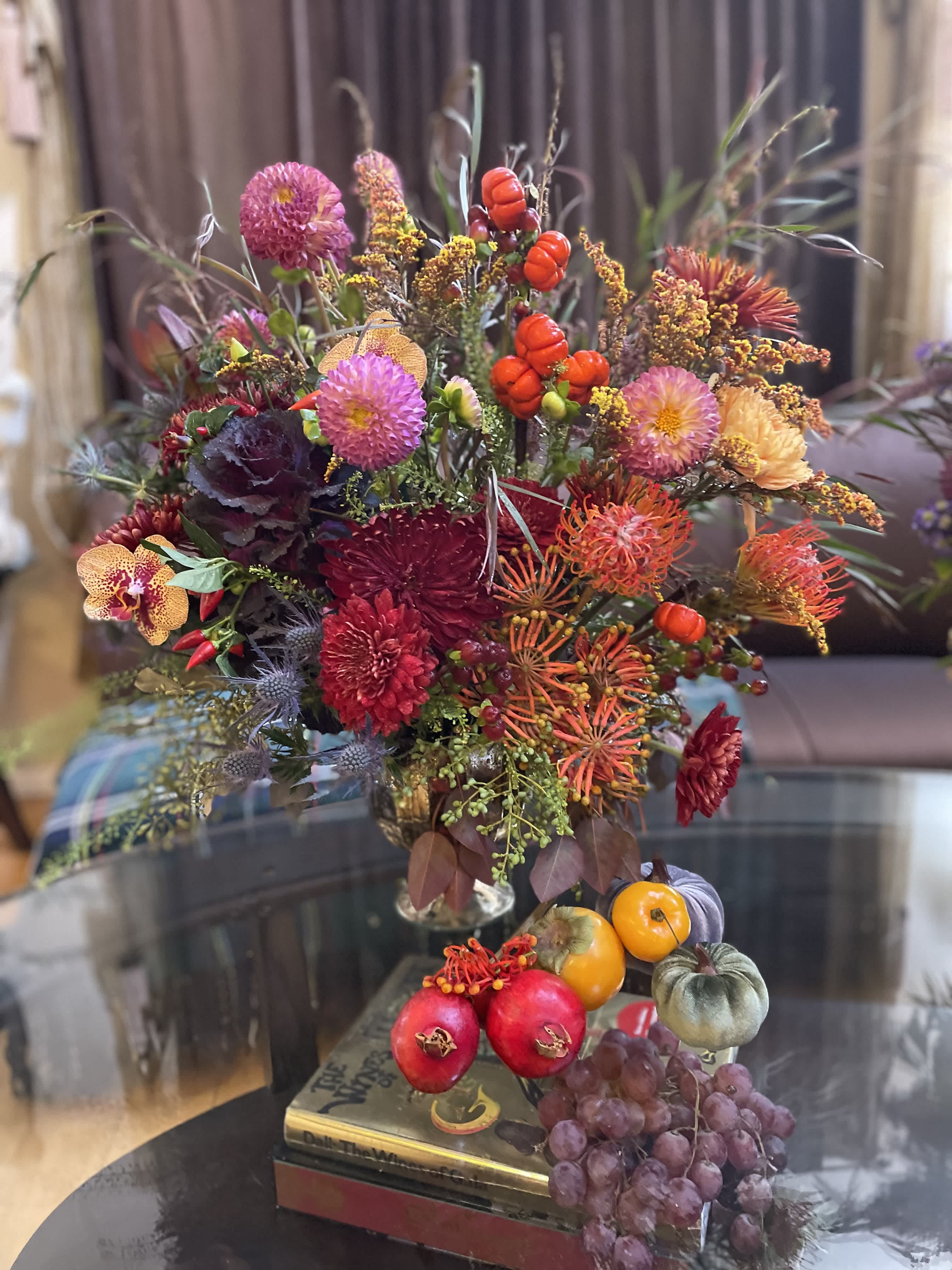 Colorful floral arrangement with pumpkins and grapes in a vase