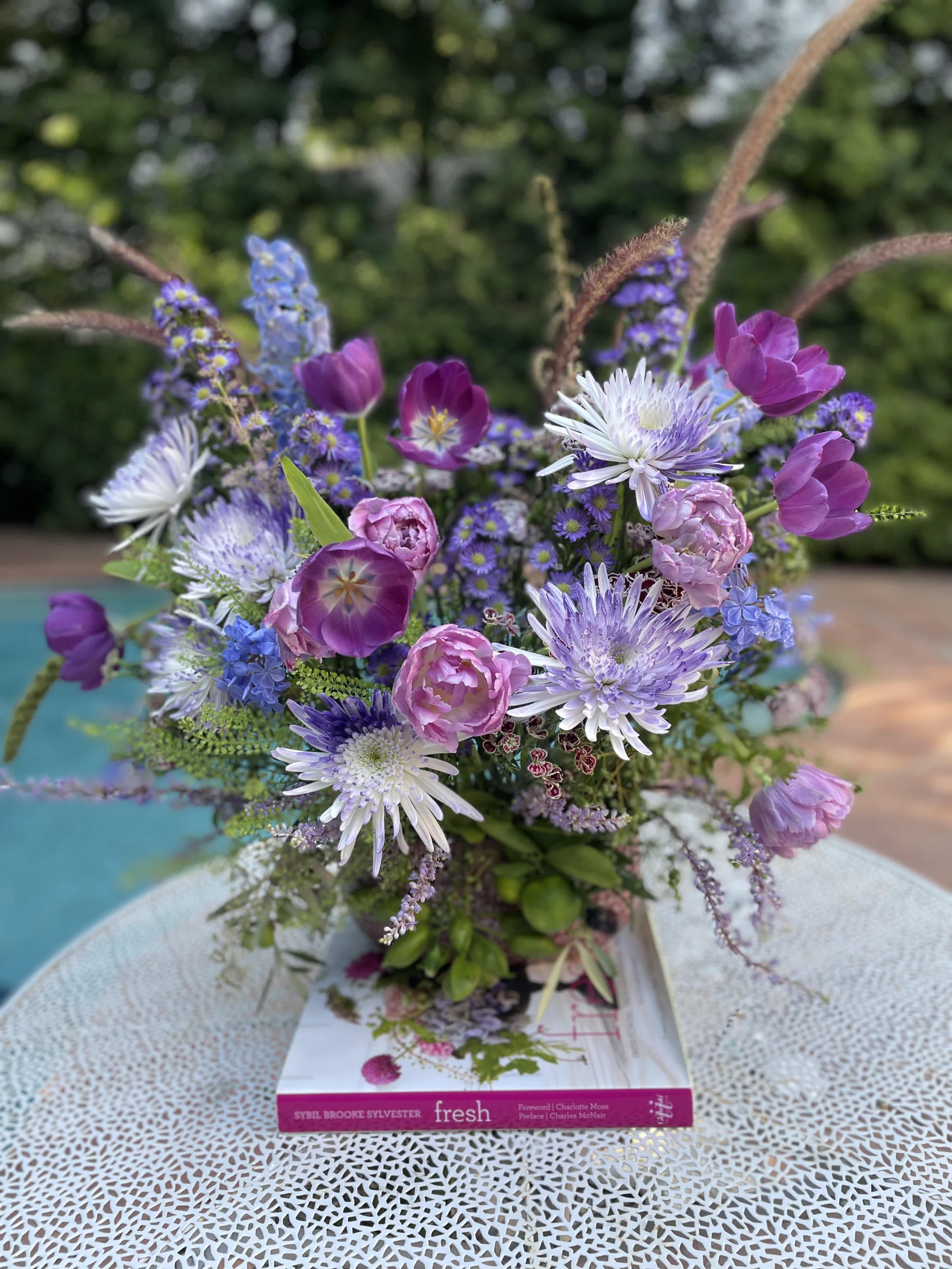 Mixed purple and pink bouquet in a vase on a book